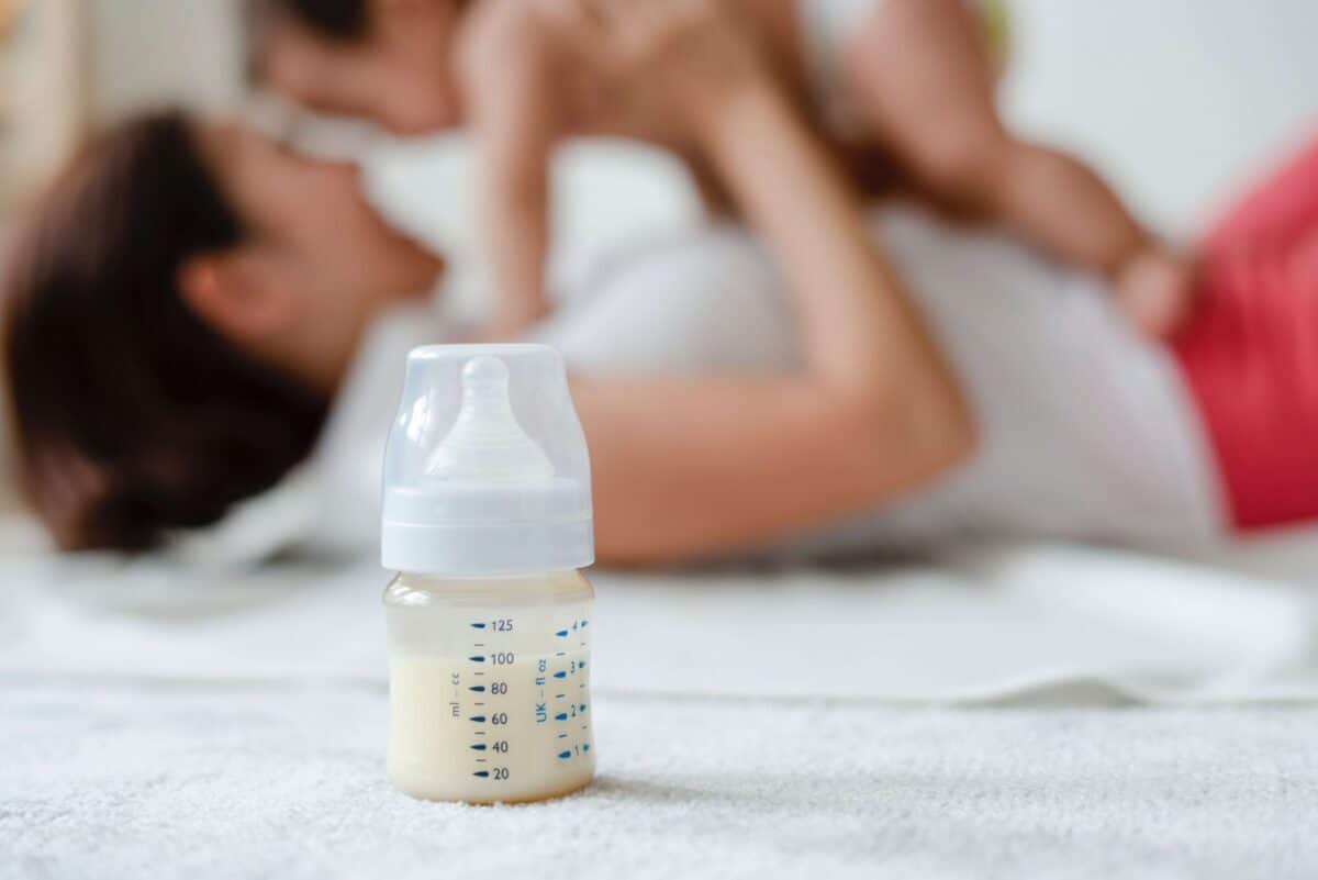 Mother holding baby with bottle of formula in the foreground