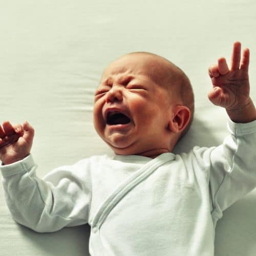 baby crying on green sheet