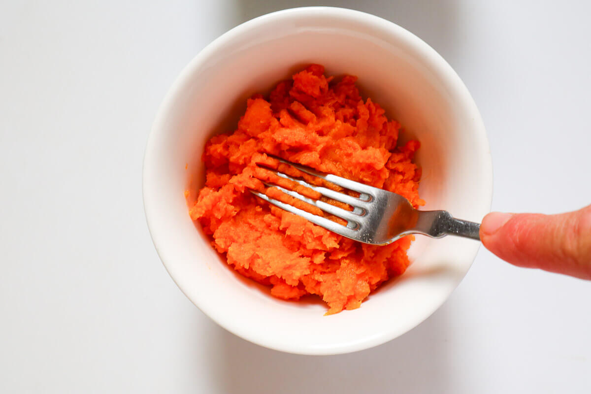 Mashing sweet potato with a fork.