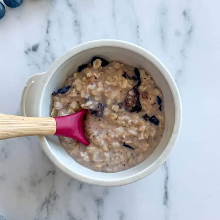 Blueberry Oatmeal with Kefir and Almond Butter in a silicone bowl with a spoon dipped in