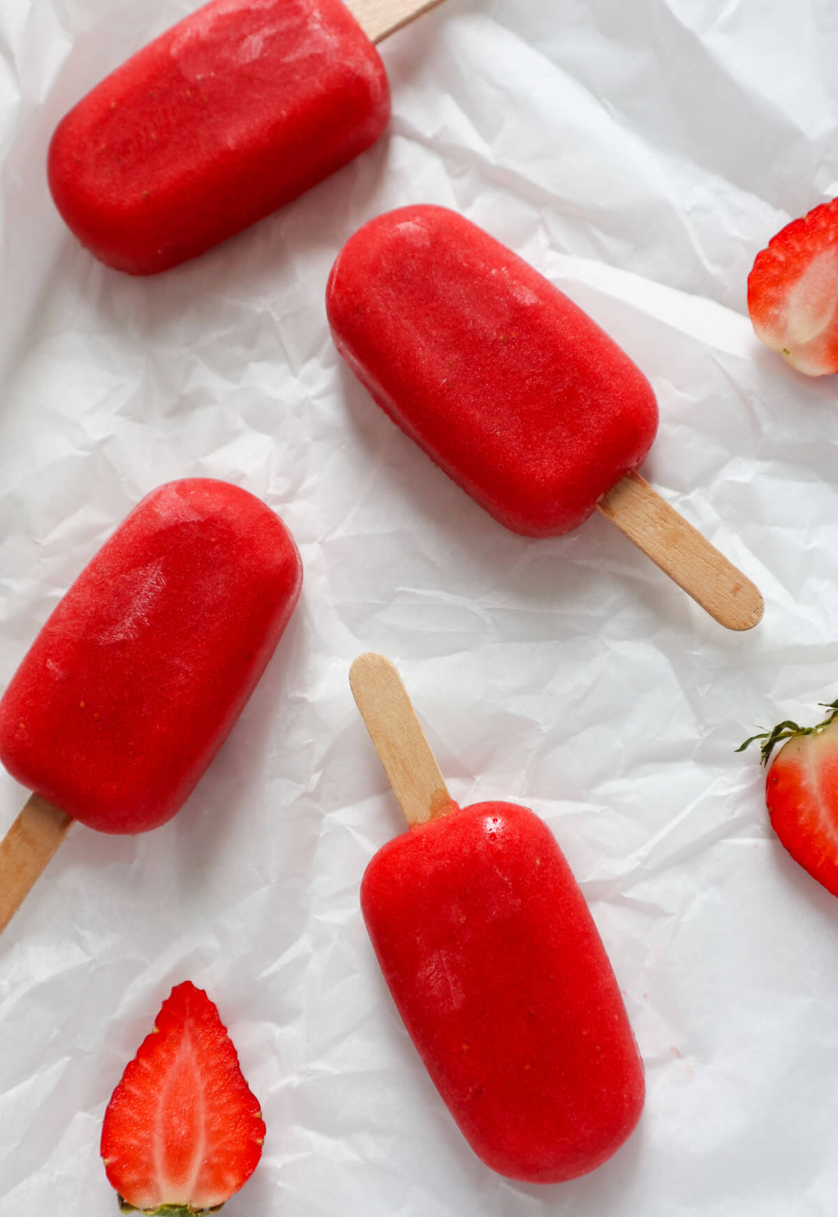 Strawberry ice cream popsicles with wooden sticks on white paper. 