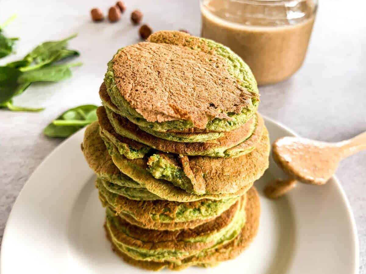spinach pancakes stacked with a spoon of hazelnut butter