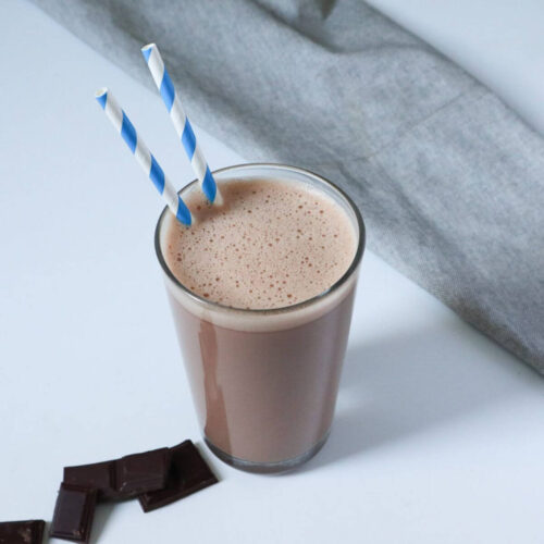 Homemade Chocolate milk in a glass with blue straws.