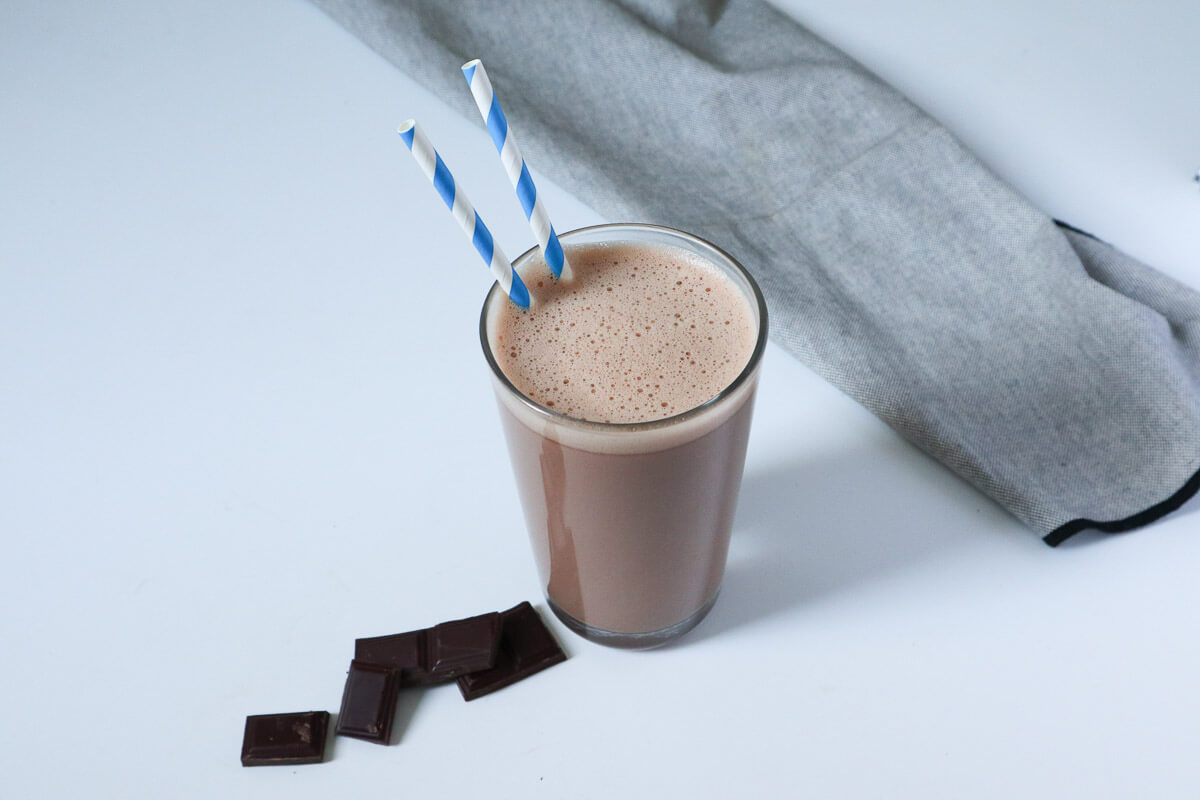Homemade Chocolate milk in a glass with blue straws.