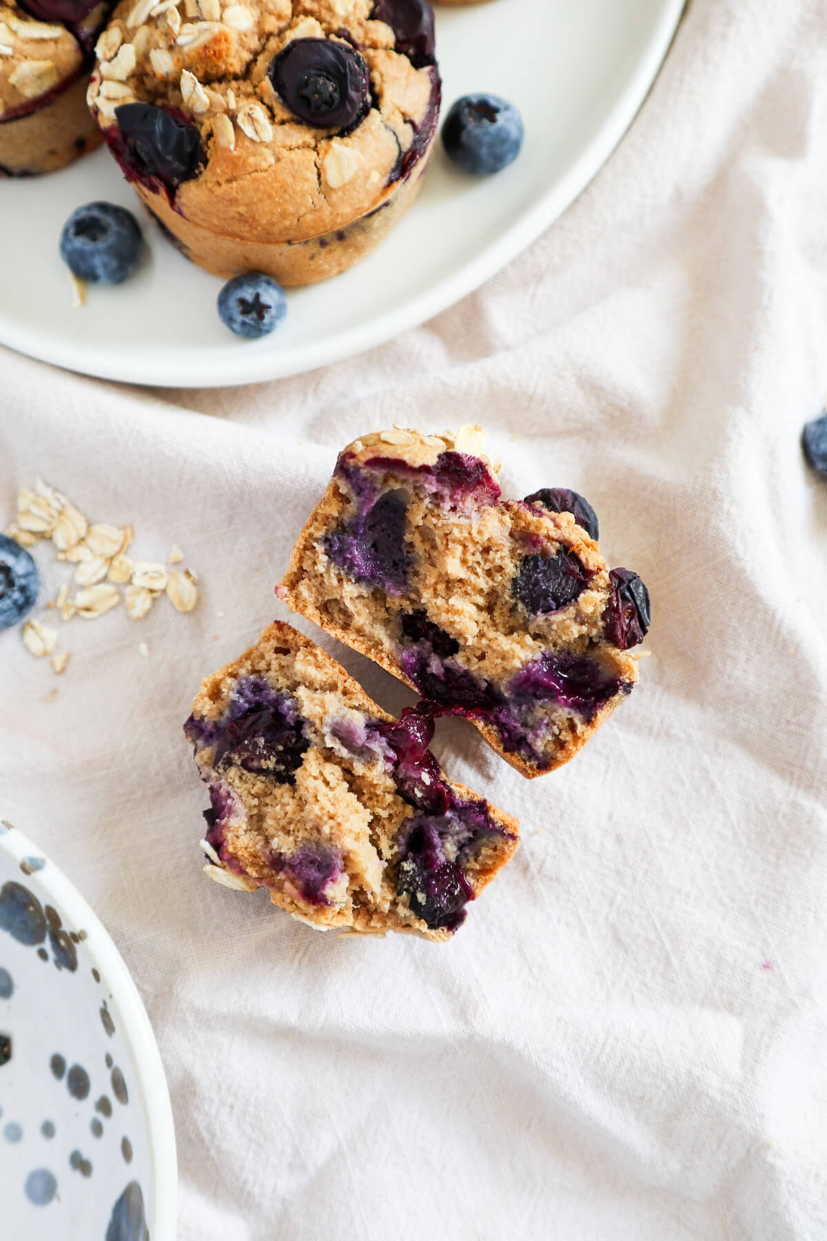 Zoomed out halved muffin with a plate of muffins on the side.