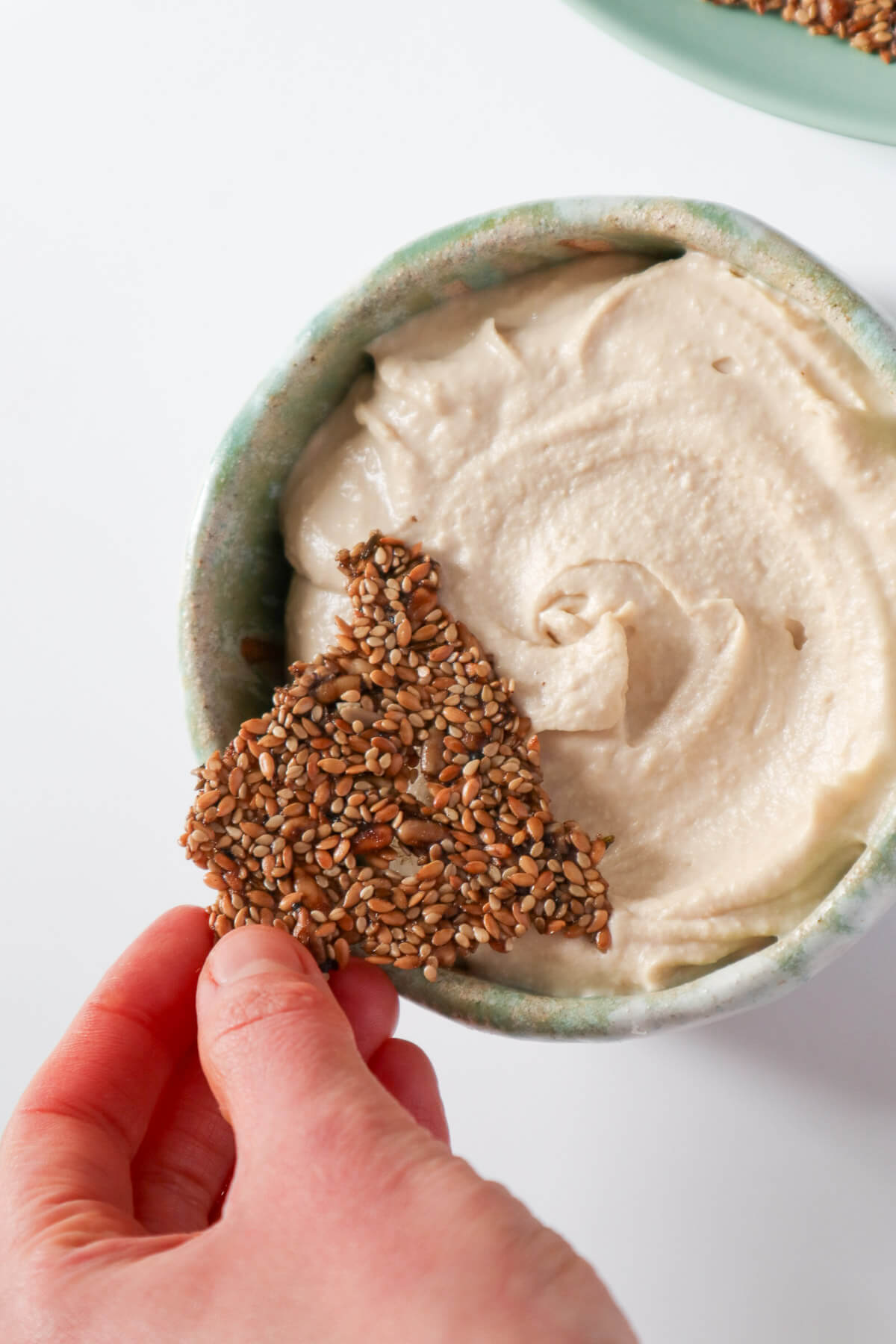 Sunflower Sesame Seed Crackers dipped in hummus. 