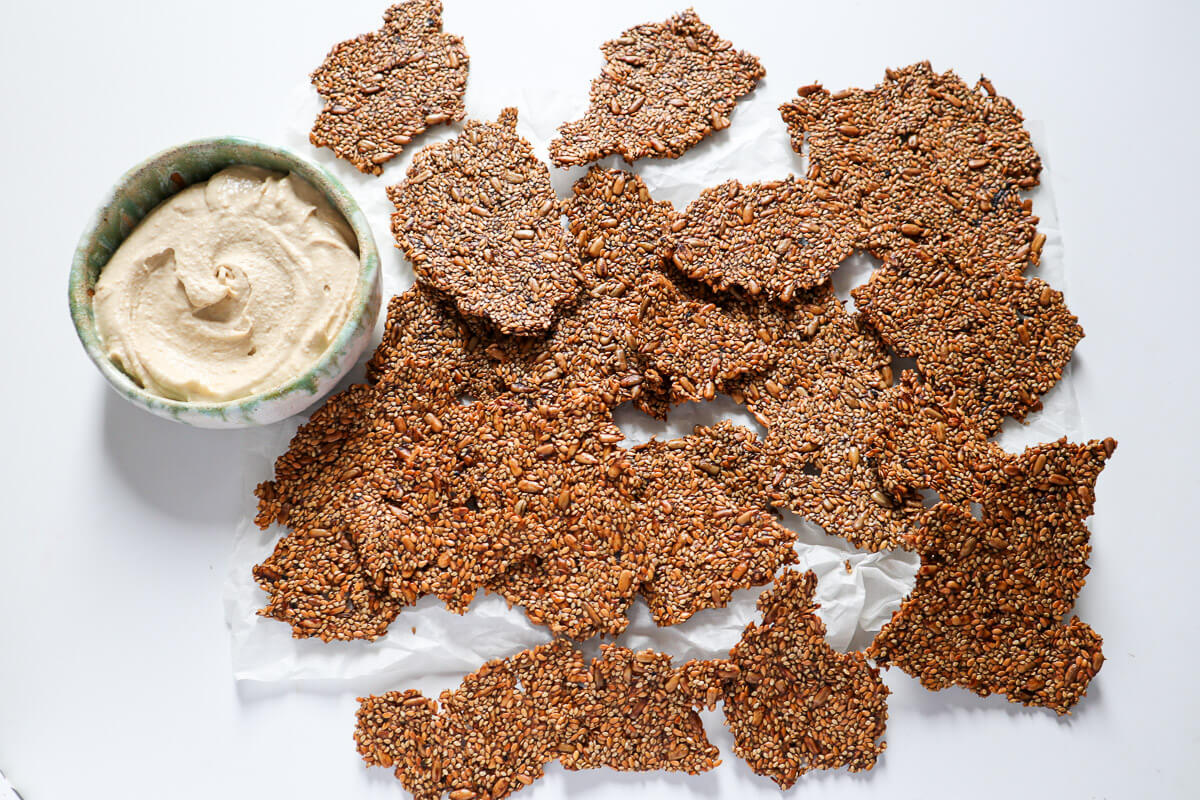 Torn apart crackers next to a bowl of hummus