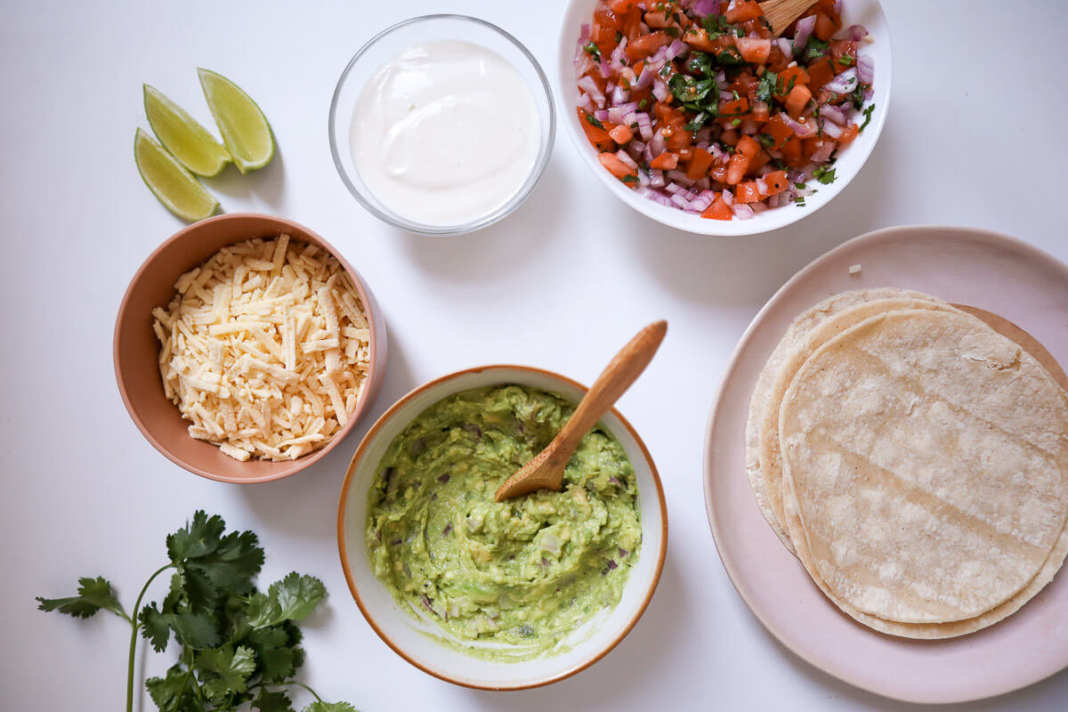 Toppings for the tofu fajitas on a white background