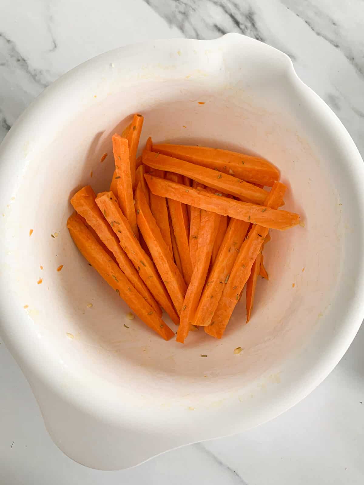 raw sweet potatoes with the oil and spices in a bowl