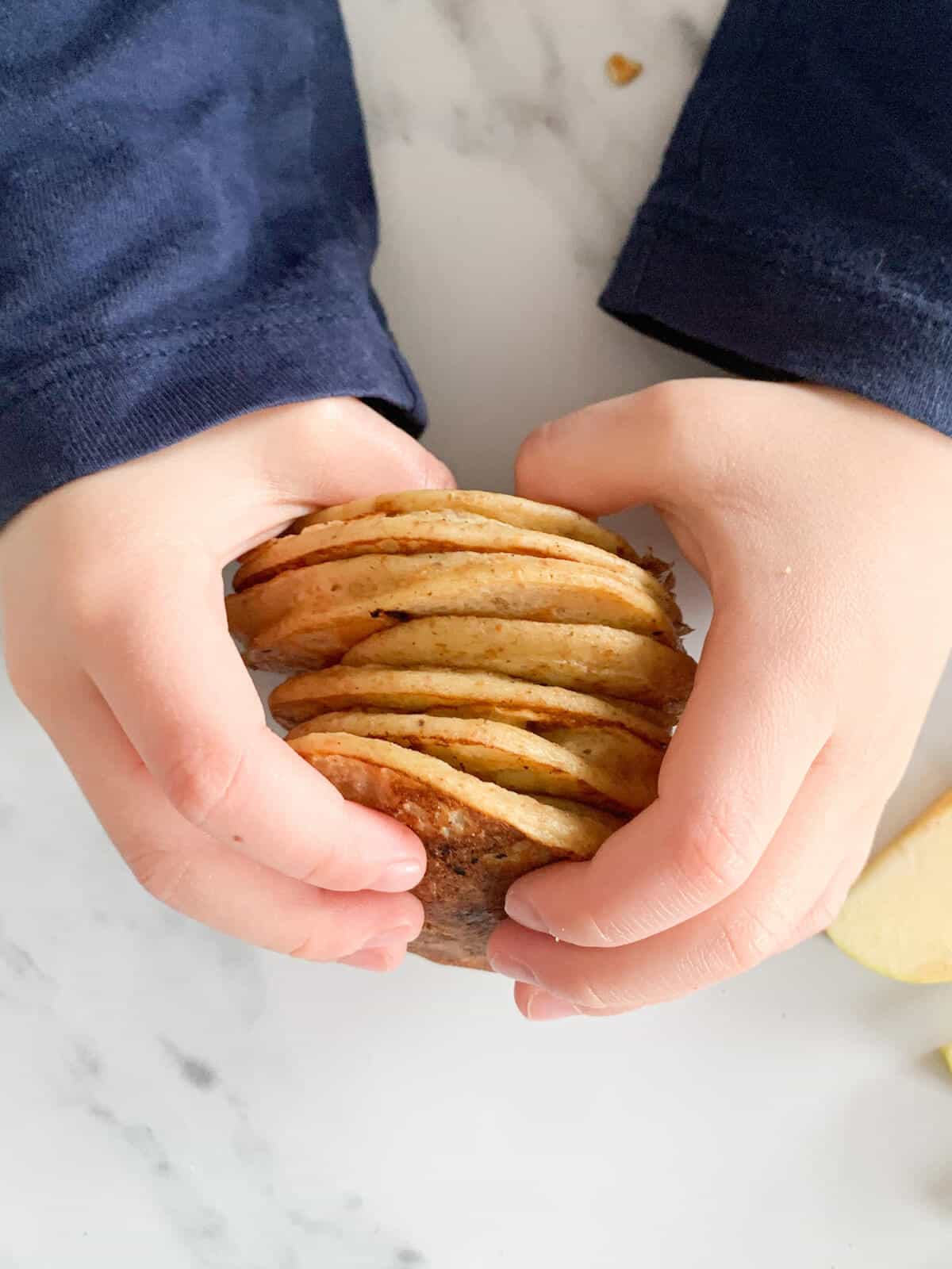 Toddler holding healthy apple pancakes 