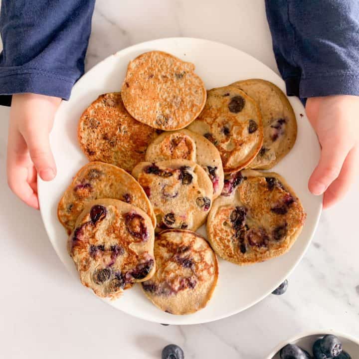 Toddler holding healthy blueberry pancakes
