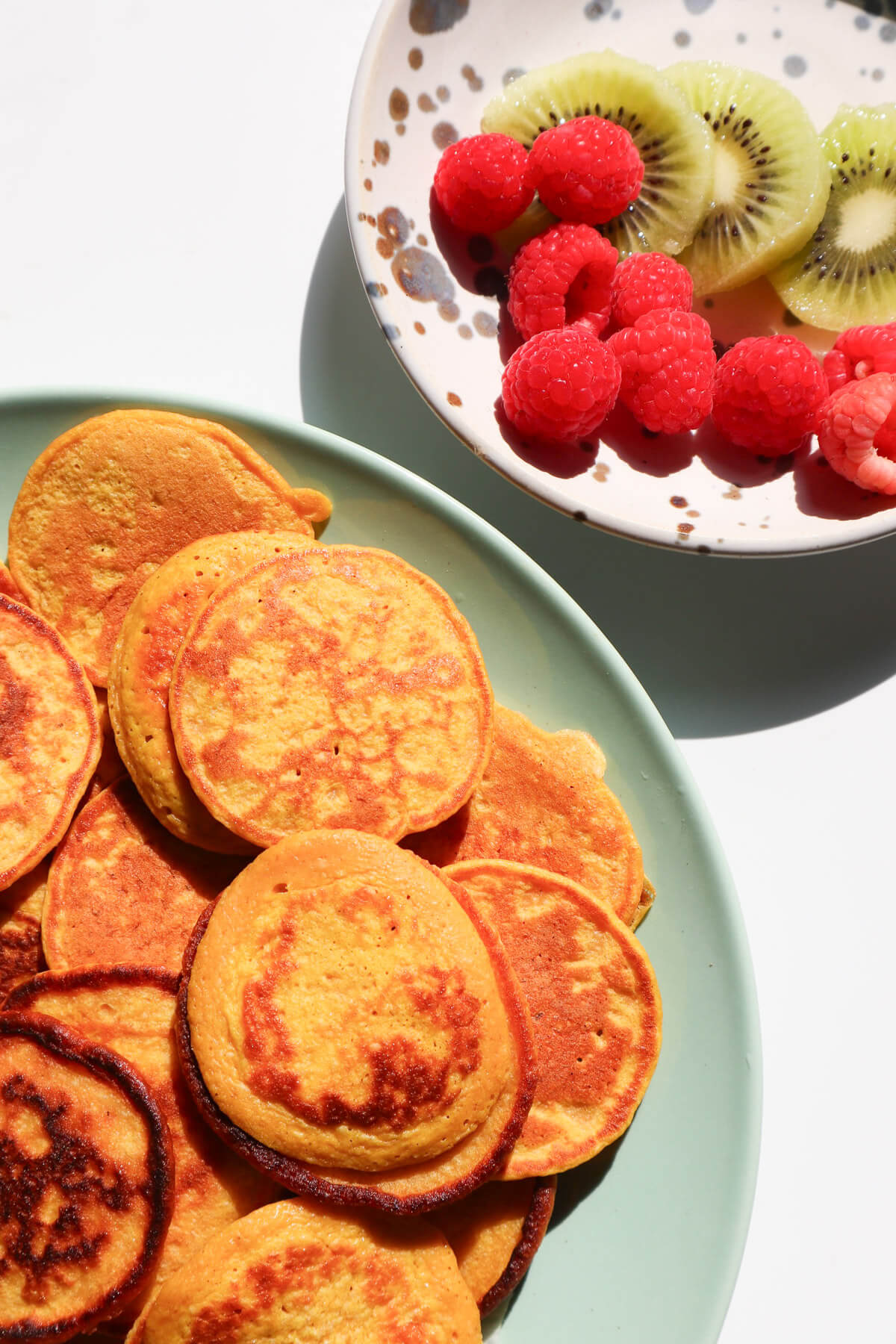 pancakes and a bowl of fruit on the side