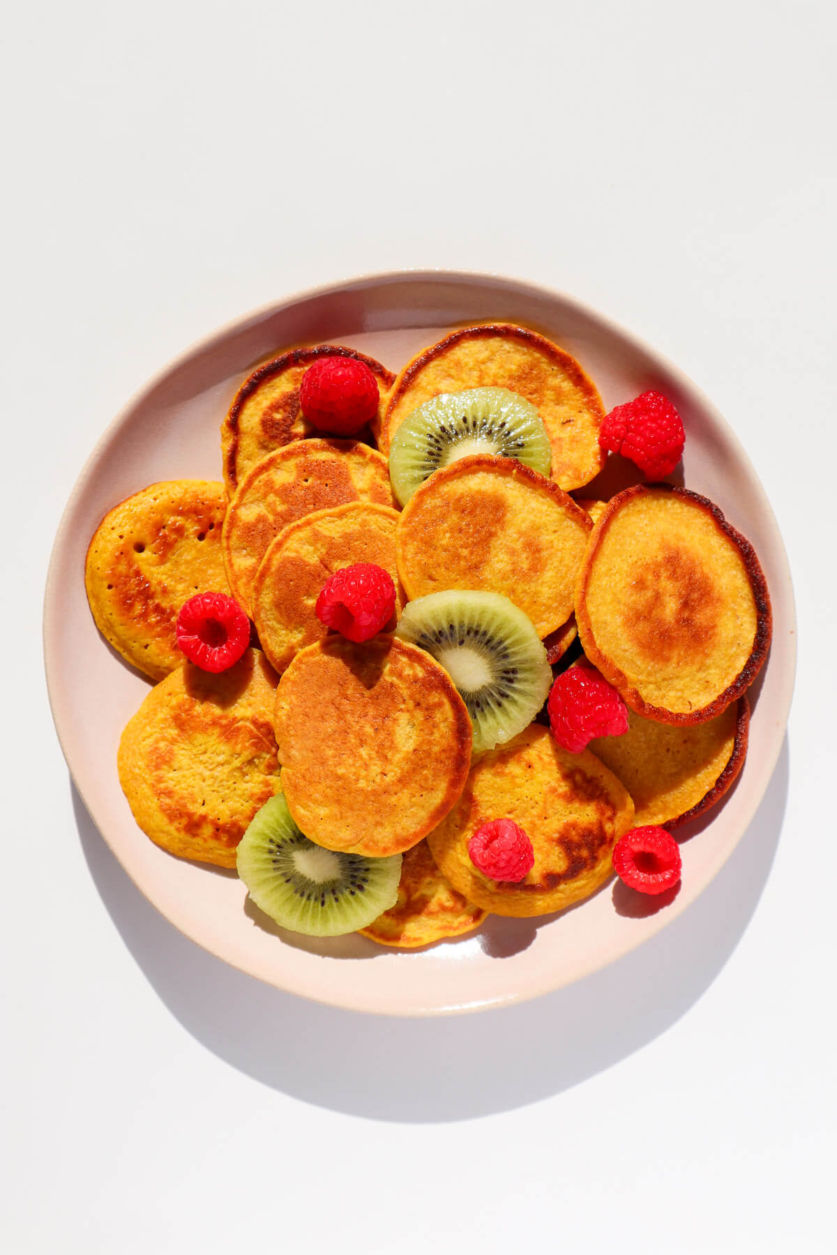 Sweet Potato Pancakes on a plate with kiwis and raspberries