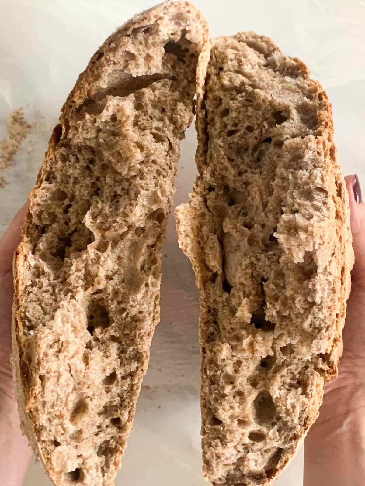 two halves of wholewheat bread pulled apart with hands