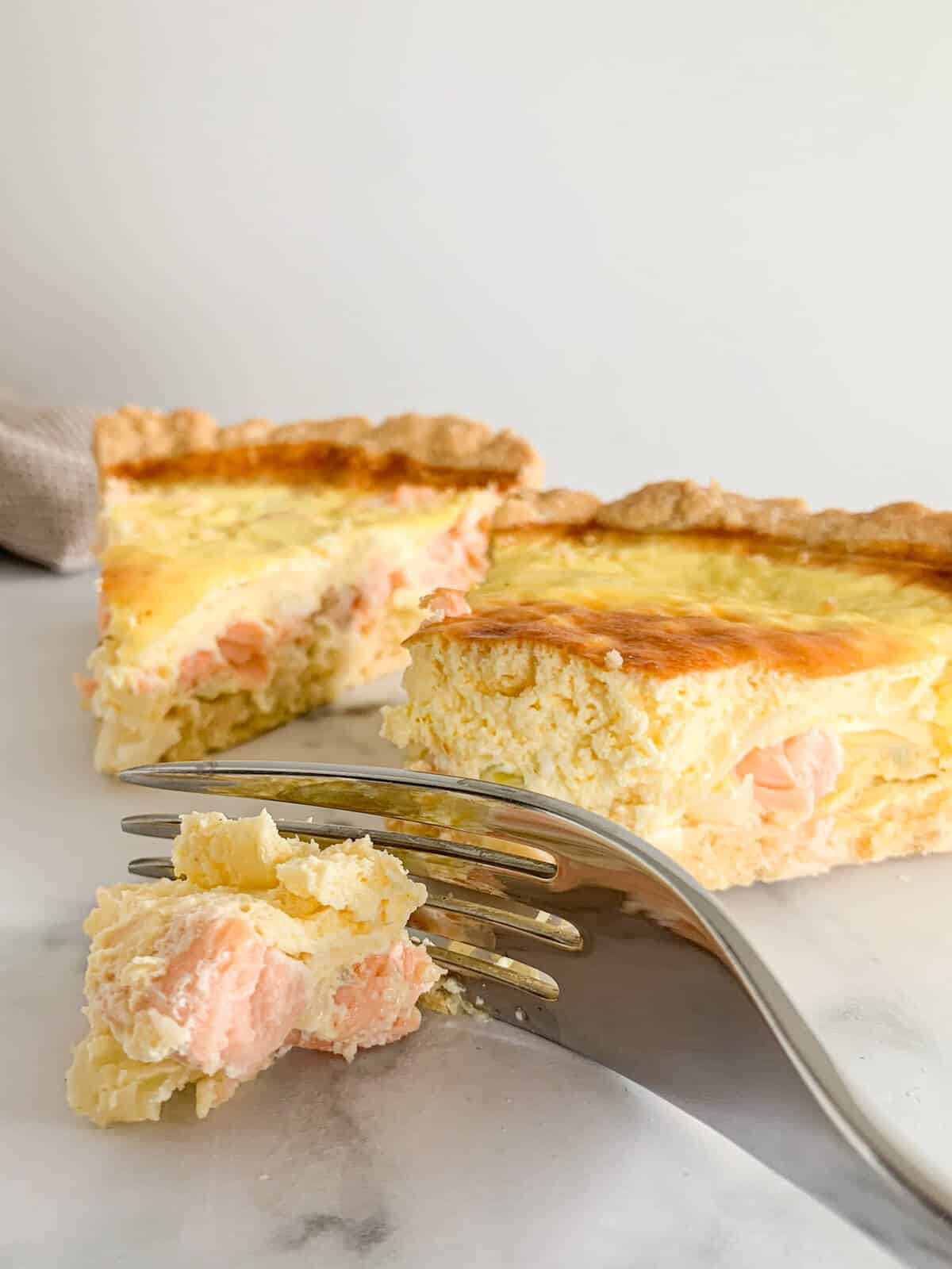 slice of salmon leek quiche with a fork cutting the end of it