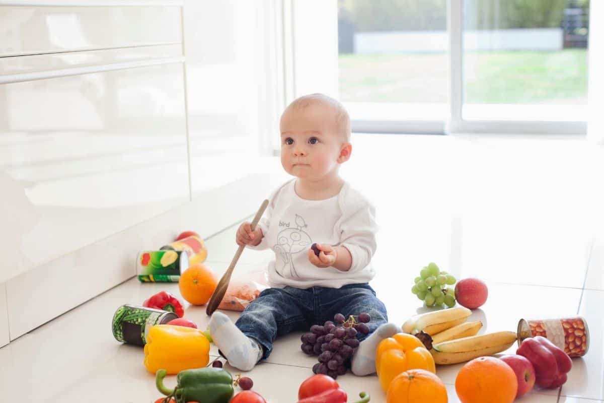 baby on floor with lots of fresh food