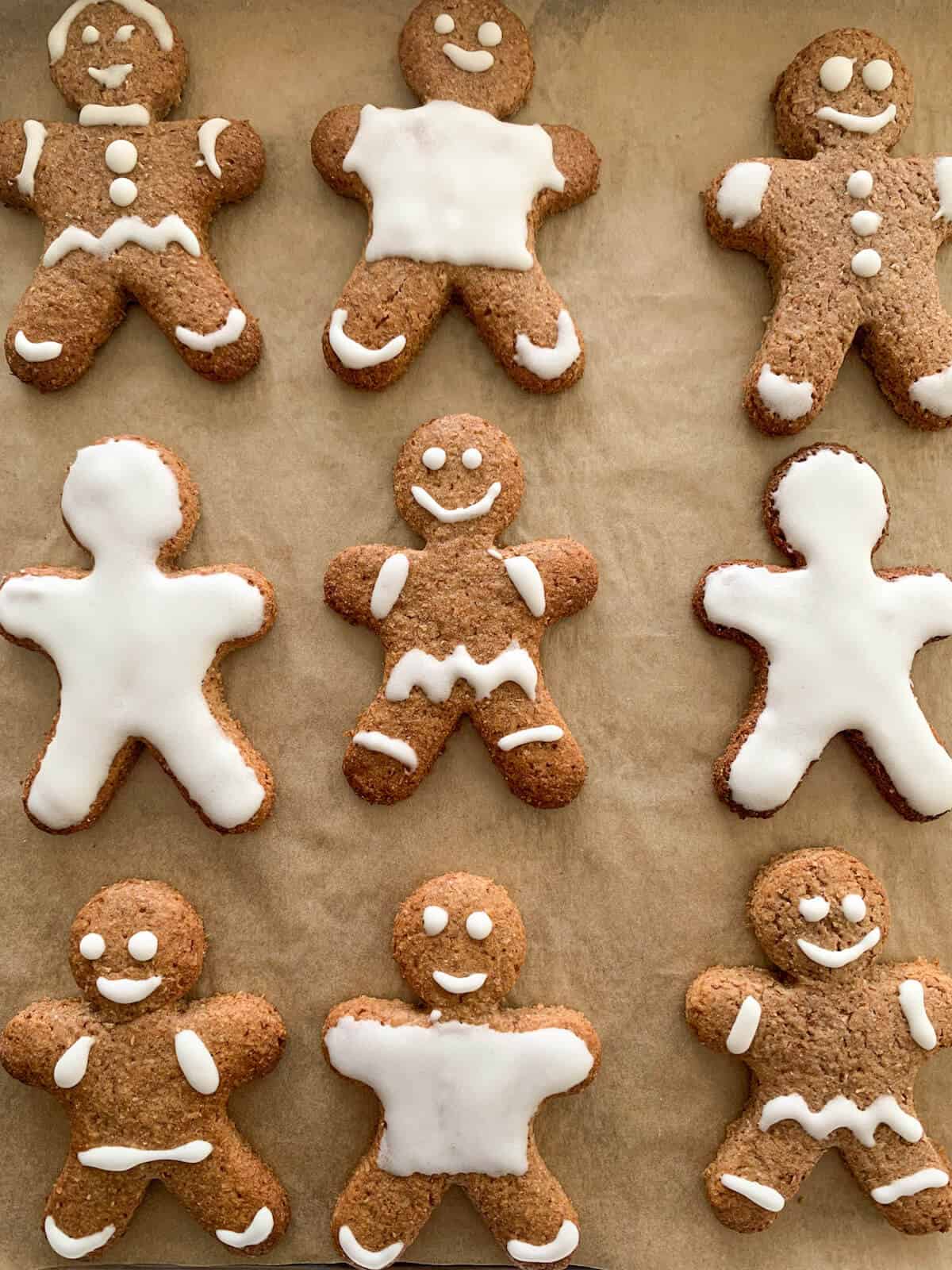 3 x 3 rows of Gingerbread men cookies decorated with white royal icing by kids