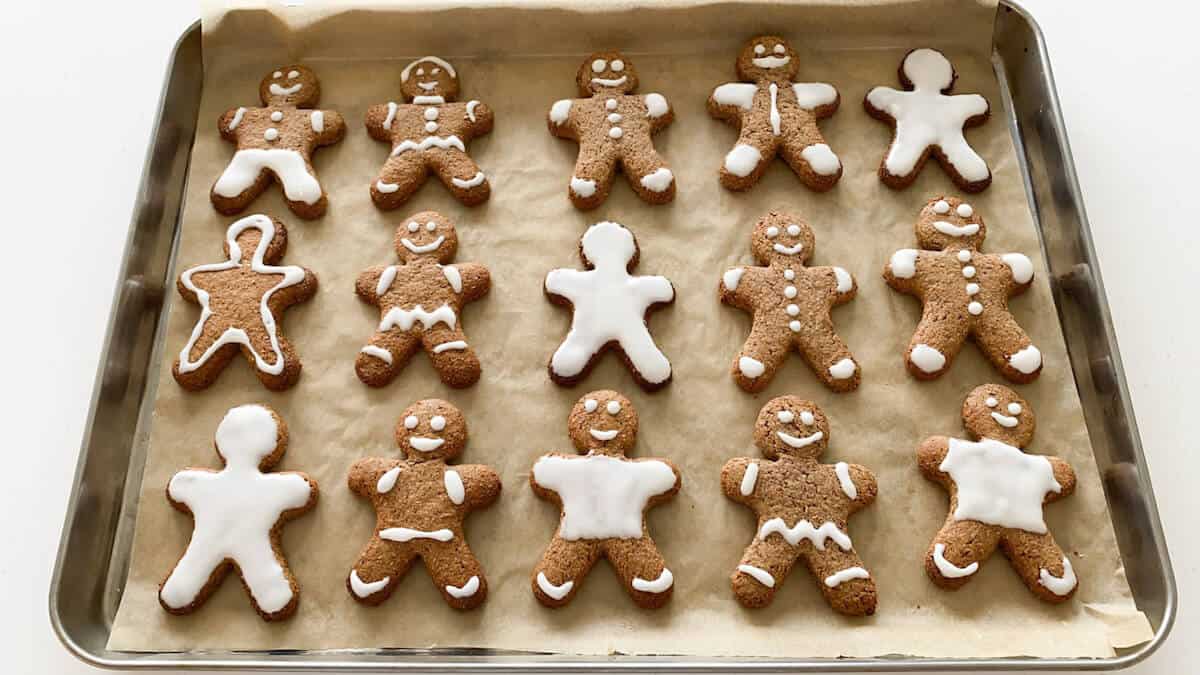 15 decorated gingerbread men cookies on a stainless steel baking tray 