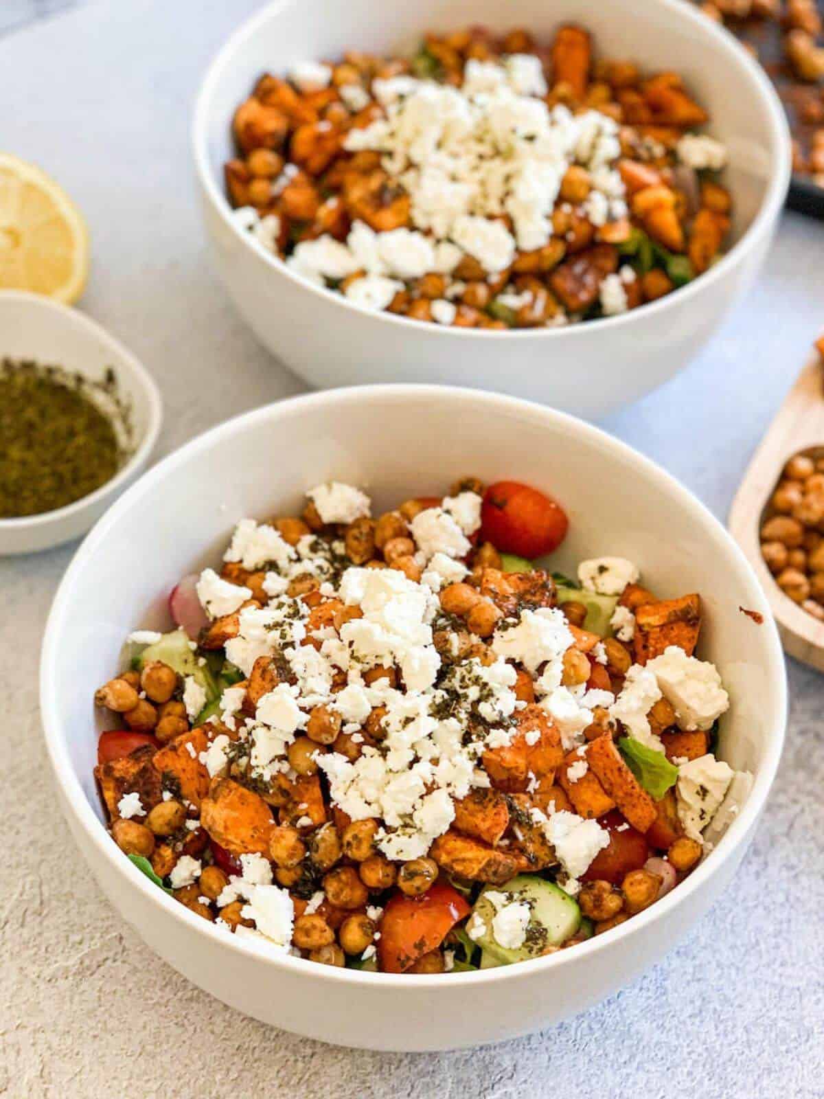 sweet potato salad with feta and mediterranean mint dressing in a white bowl, second bowl with salad in background