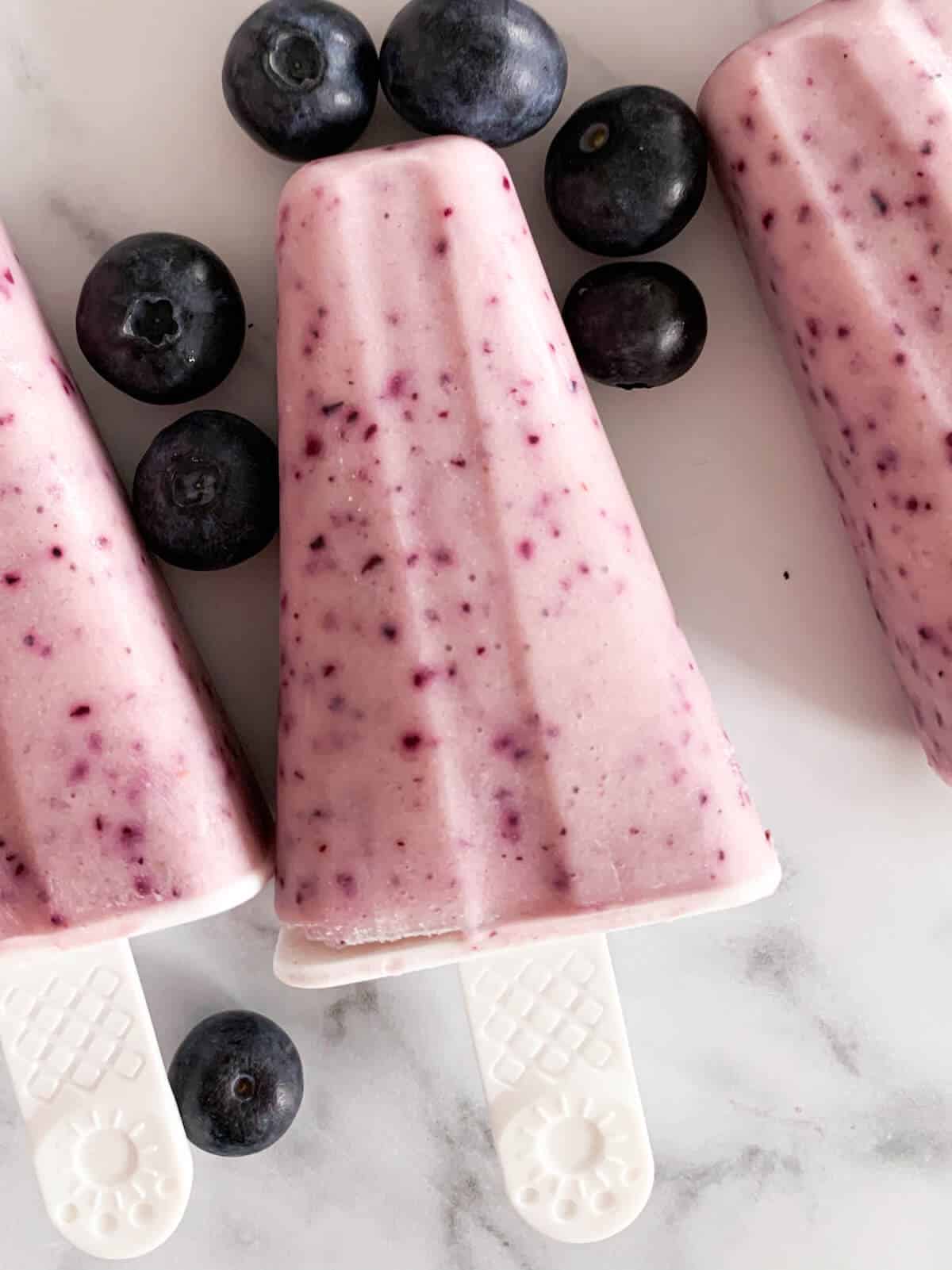 centered fruit popsicle surrounded by a popsicle on each side 