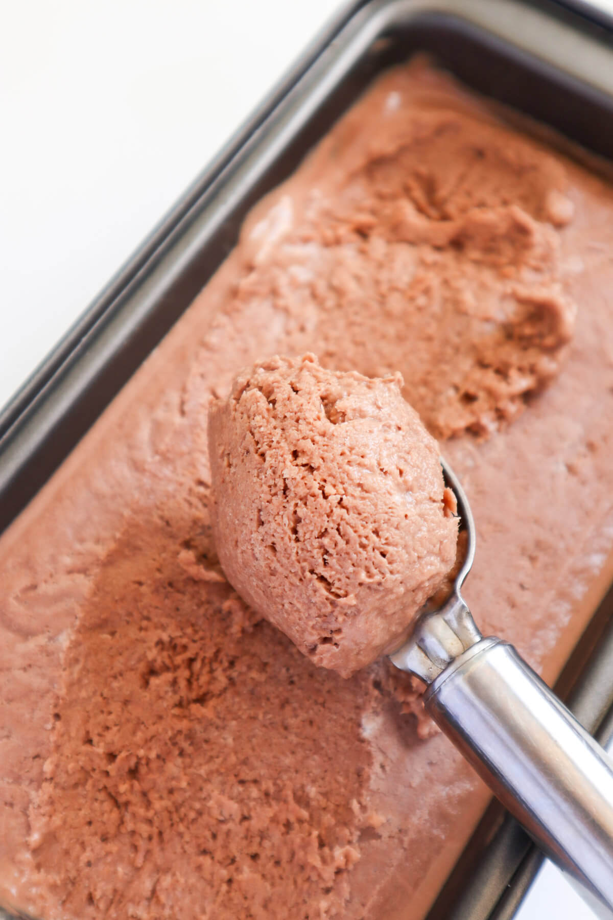 ice cream scoop scooping out ice cream from a tub