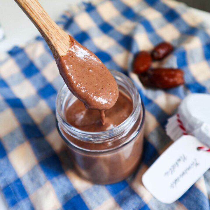 Homemade chocolate spread in a jar with wooden spoon dipped in.
