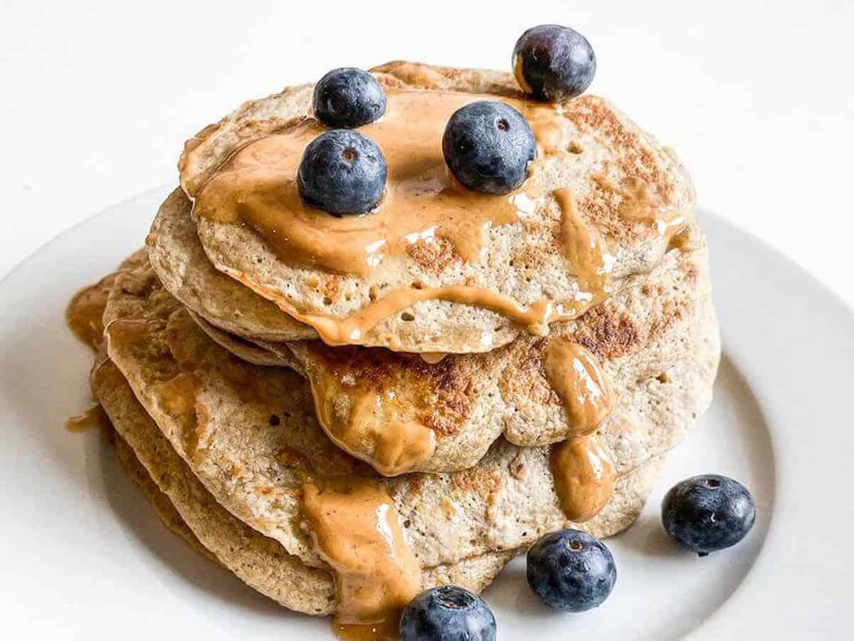 banana oat pancakes stacked with peanut butter and blueberries 