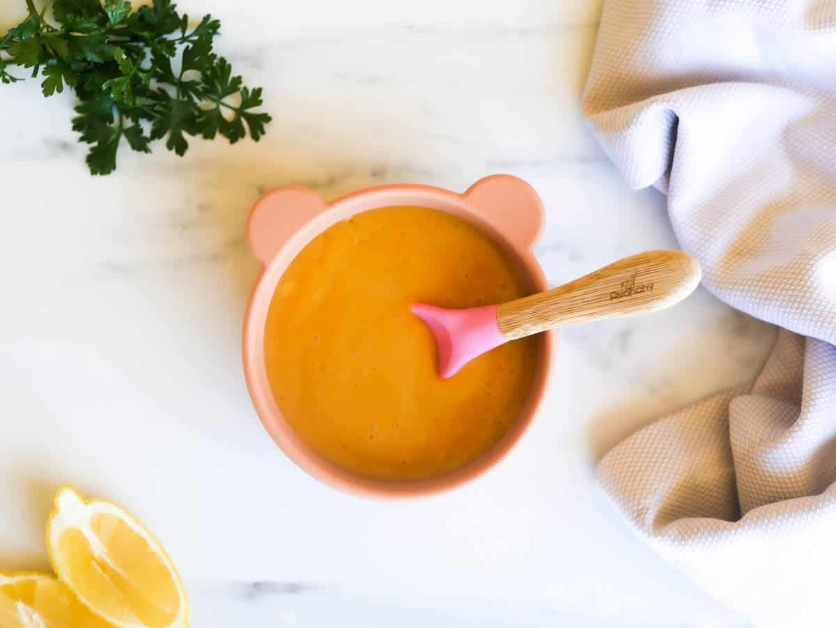 healthy red lentil baby soup in a silicone baby bowl with a silicone pink spoon