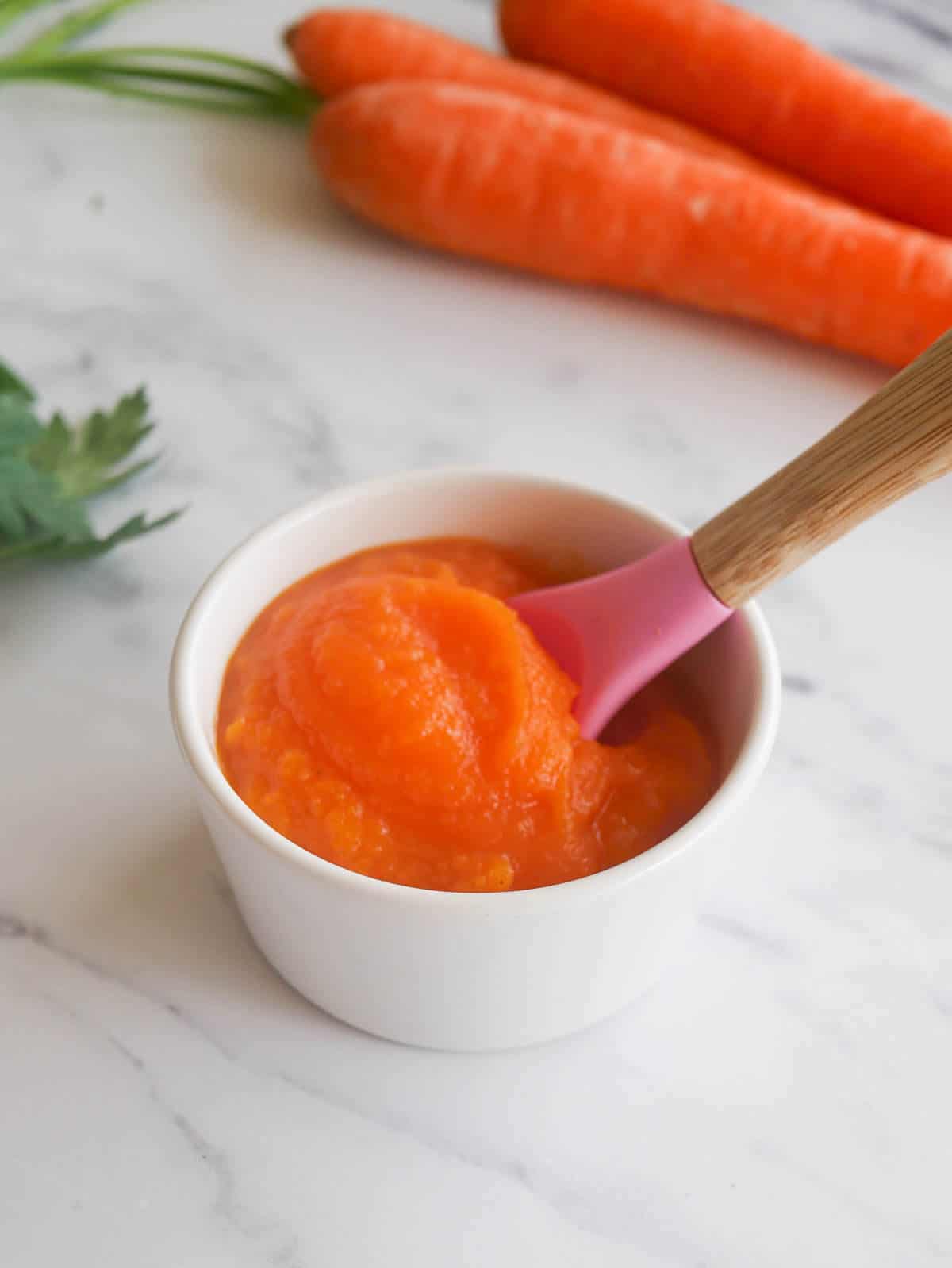 carrot puree for baby in a small bowl with a silicone baby spoon 