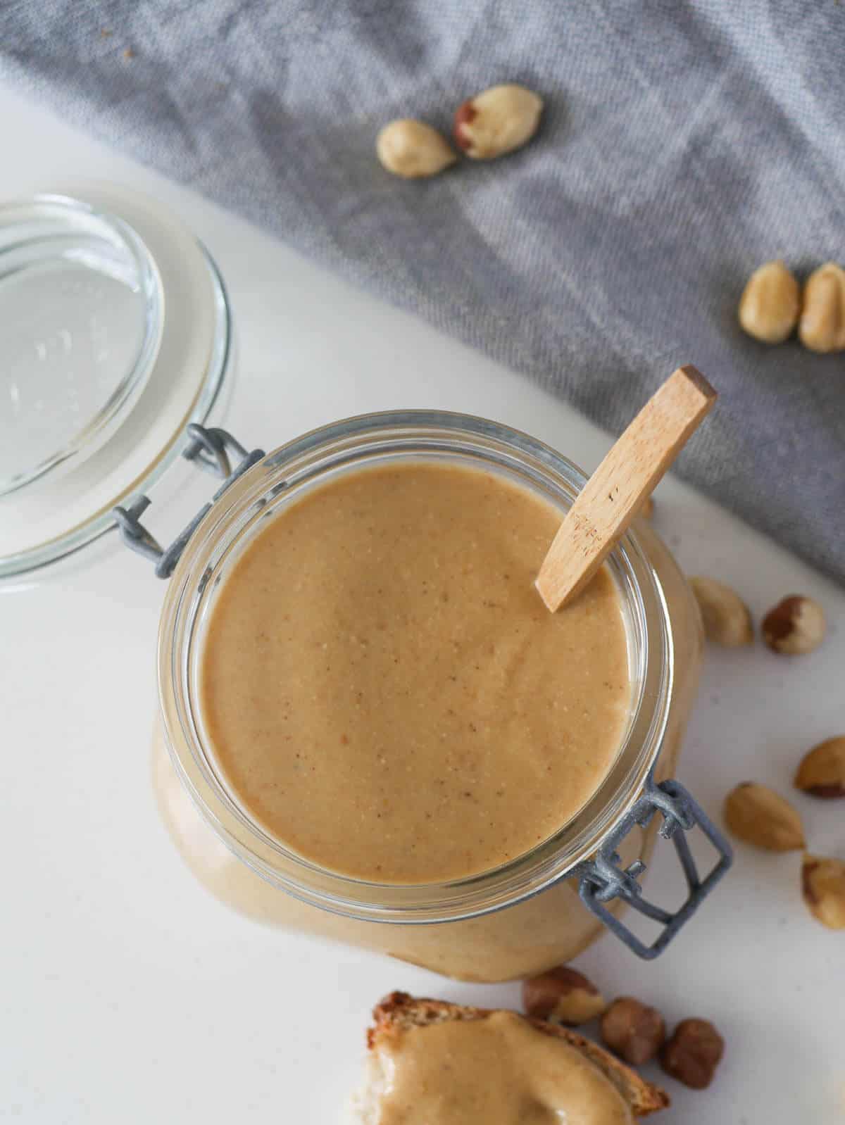 hazelnut butter in glass jar with wooden spoon dipped inside 