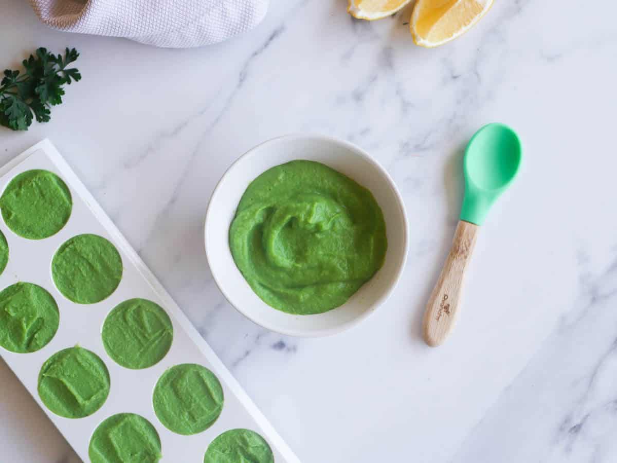 pea puree in small bowl next to an ice tray with portions of pea puree ready for freezeing 