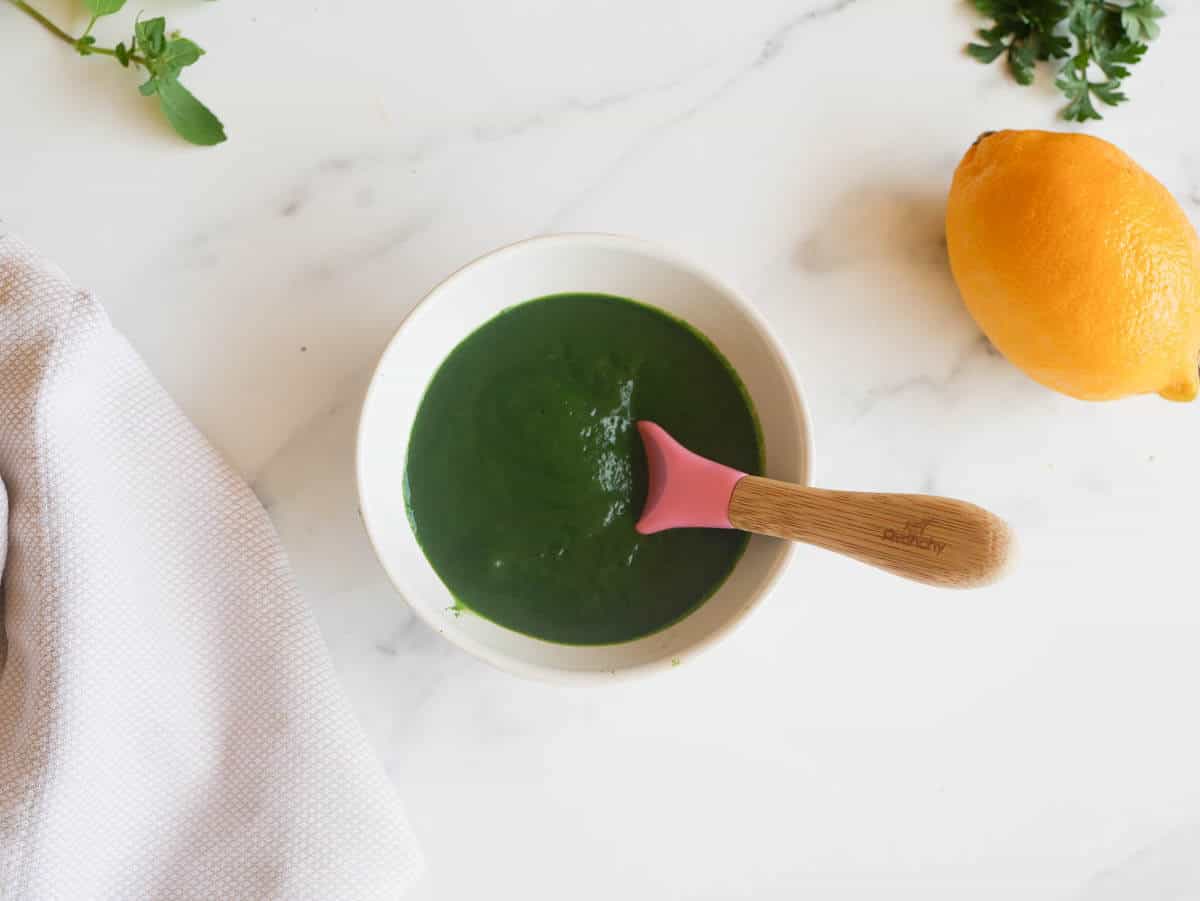 spinach puree in a bowl with a silicone baby spoon dipped in