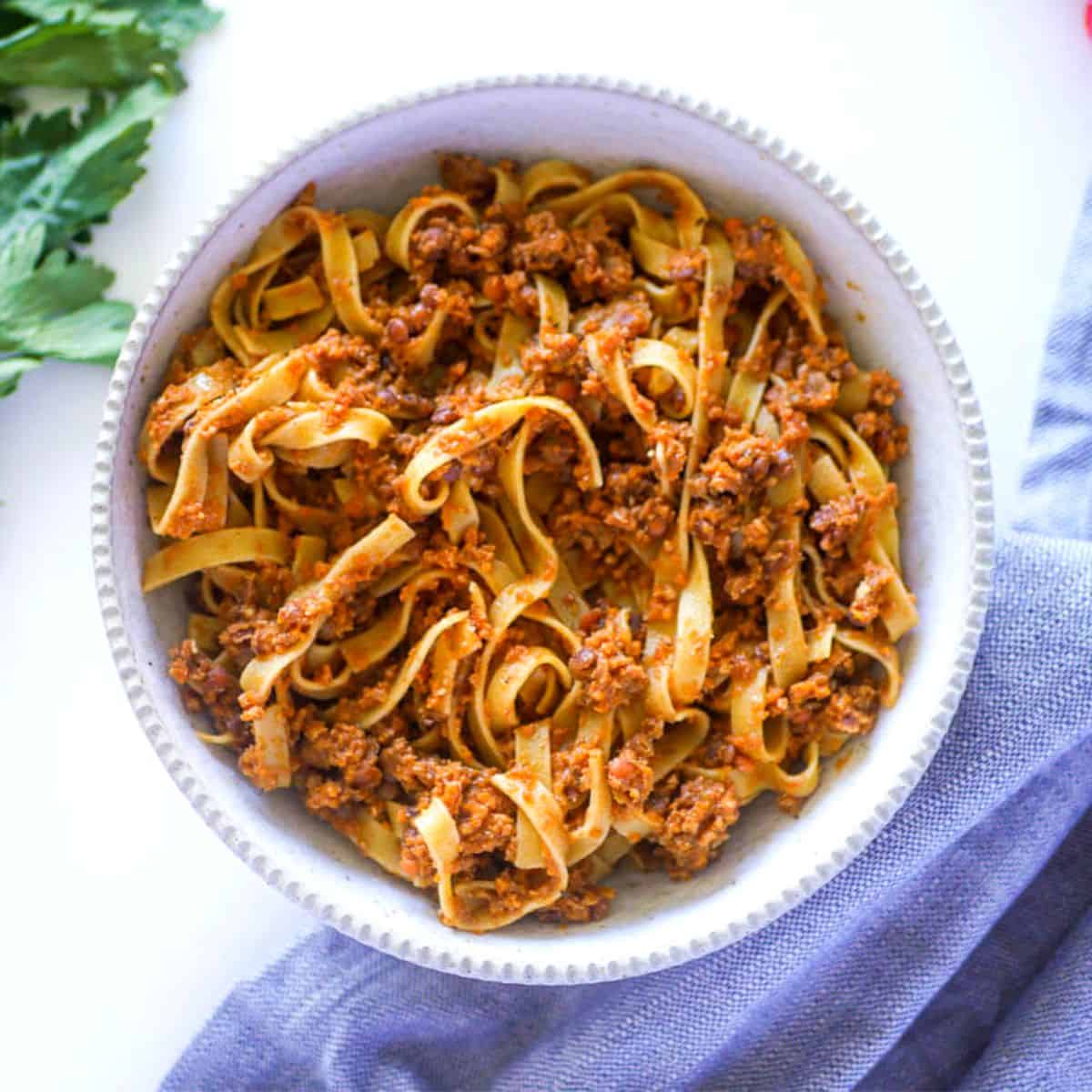 Red lentil vegan bolognese sauce in a bowl with tagliatele