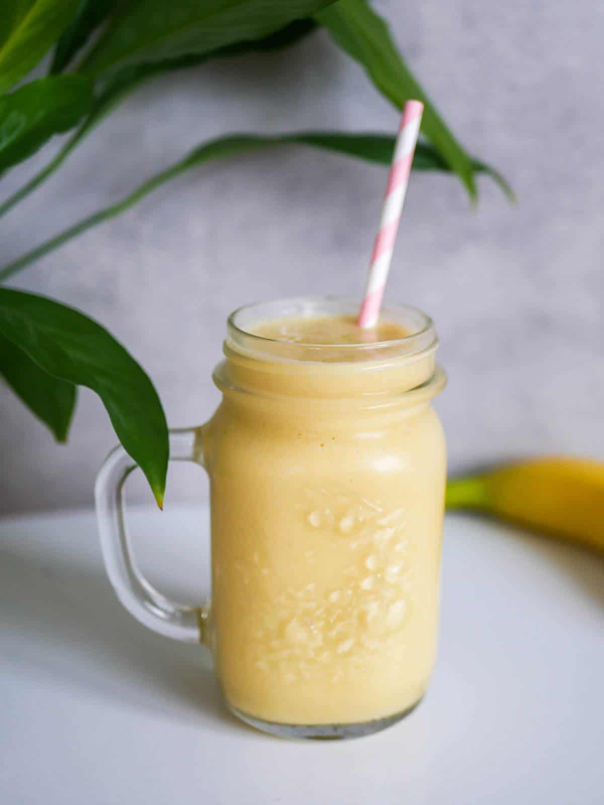 Mango Pineapple Smoothie in a glass with pink straw 