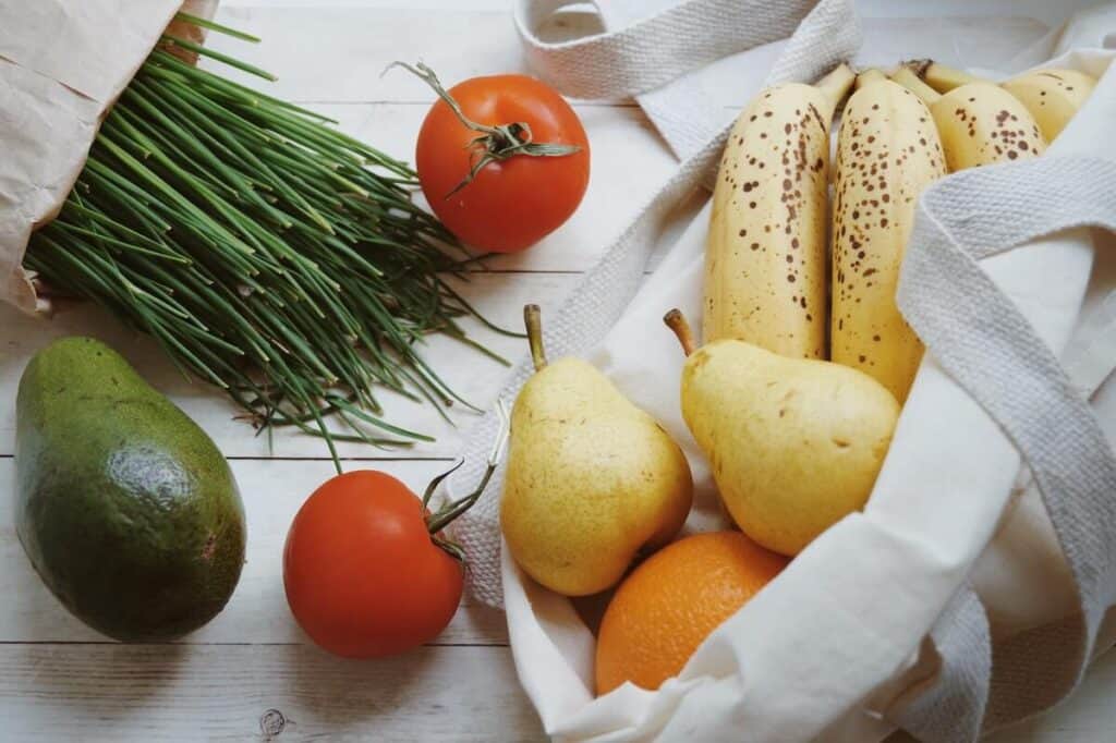 chives, pears, tomato, orange and bananas on a white background