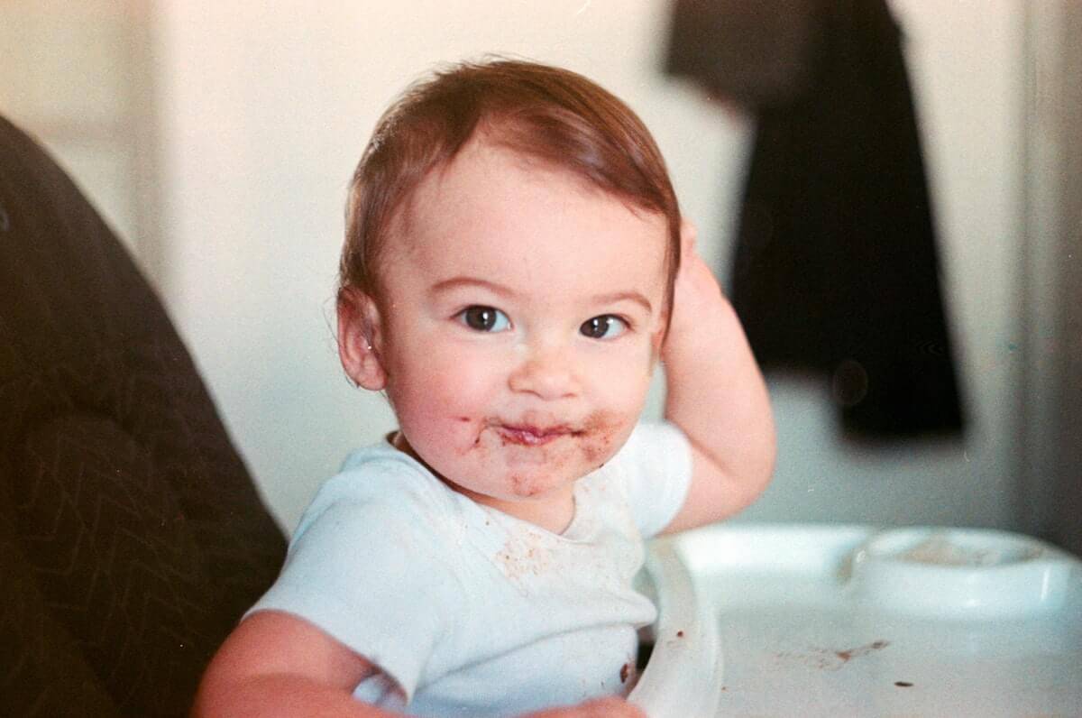 baby in high chair smiling with food on their face