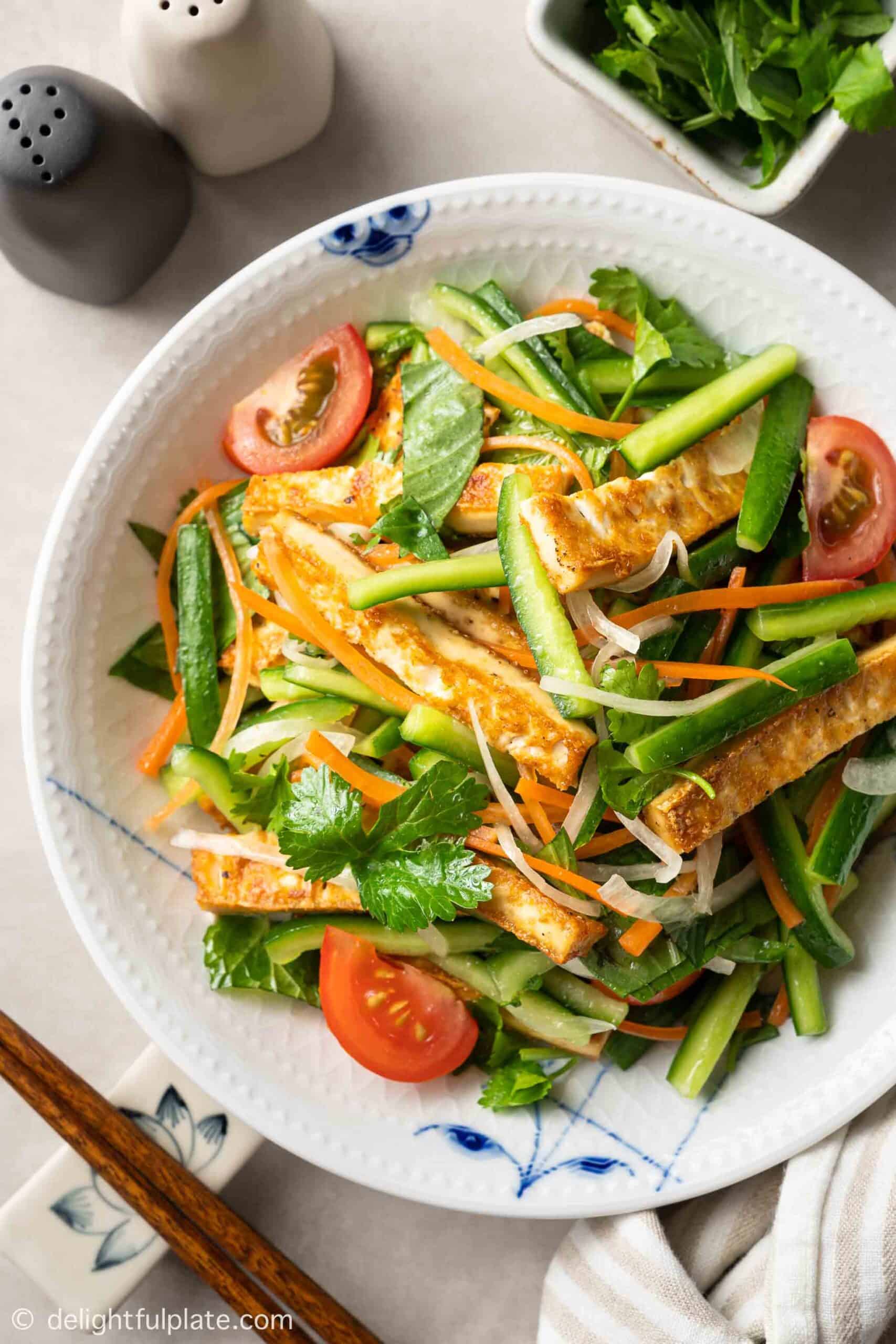 tofu salad with cucumber, tomatoes and carrots in a white bowl 