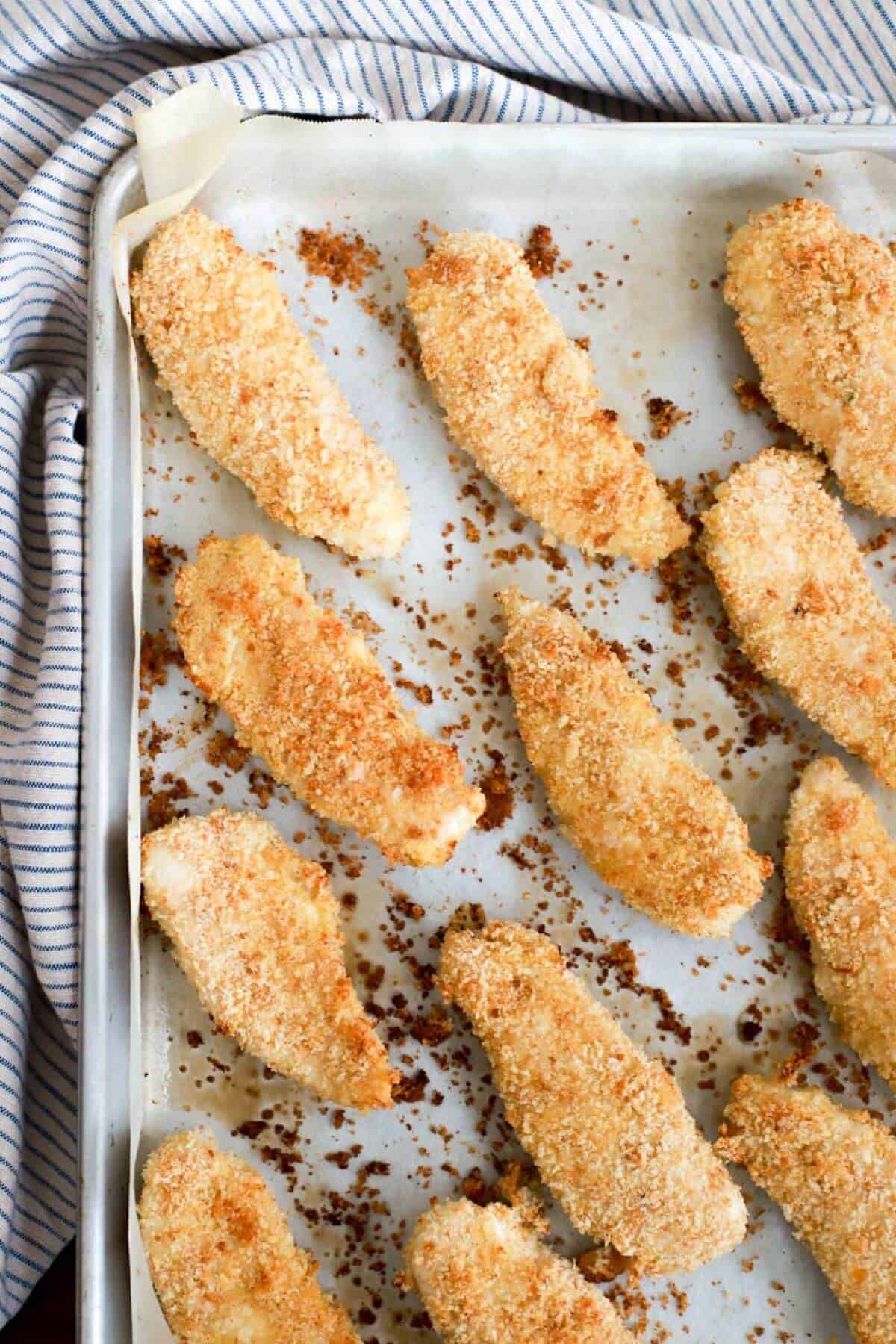 Baked chicken tenders on parchment paper.