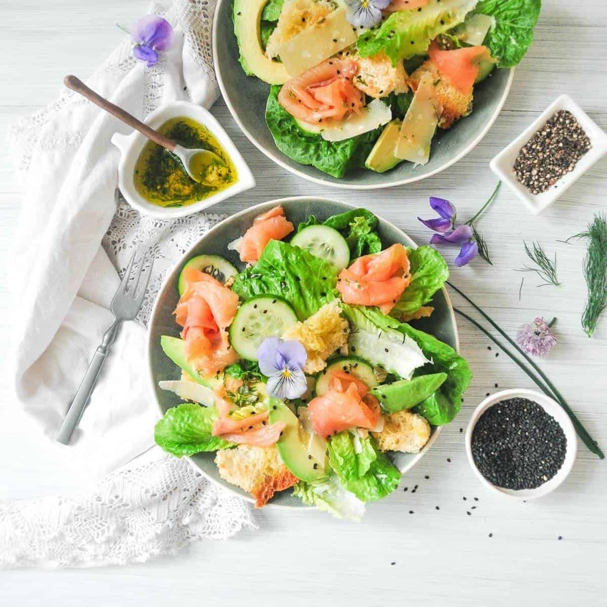 Caesar salad with lettuce, cucumbers, avocado and smoked salmon. Olive oil on the side and some chia seeds. 