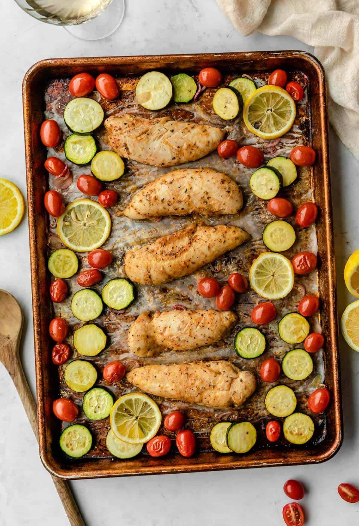 Baked chicken tenders with zucchini and cherry tomatoes in a pan. 