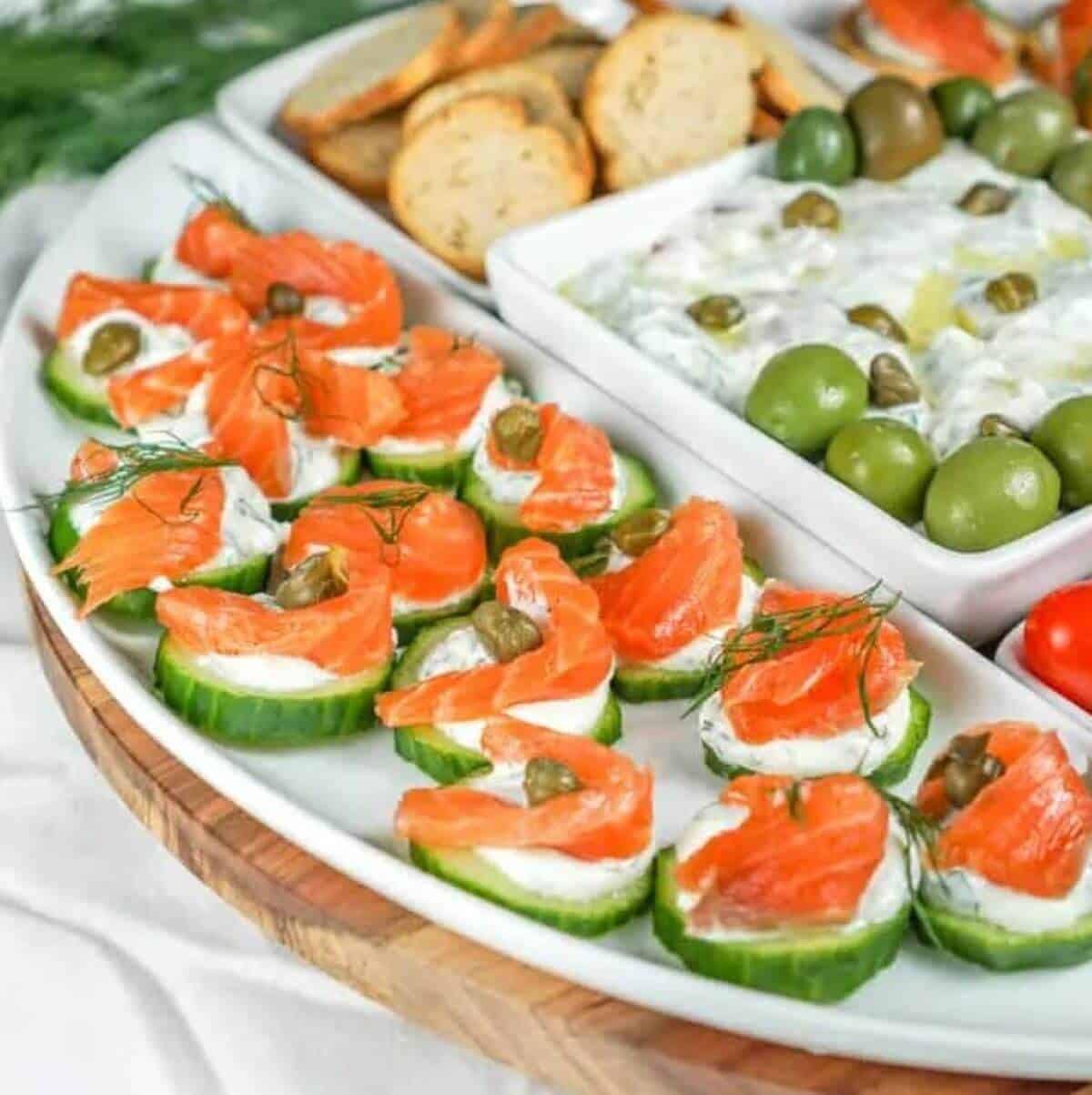 White plate with cucumber slices, smoked salmon and capers. 