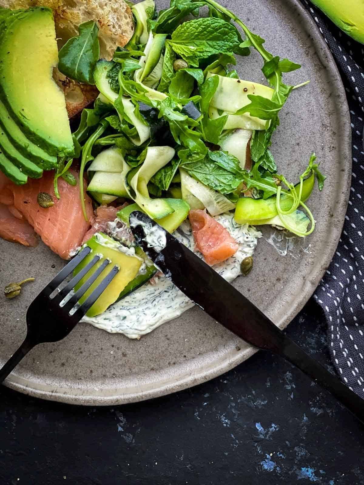 Grey plate with rocket salad, avocado and smoked salmon. 