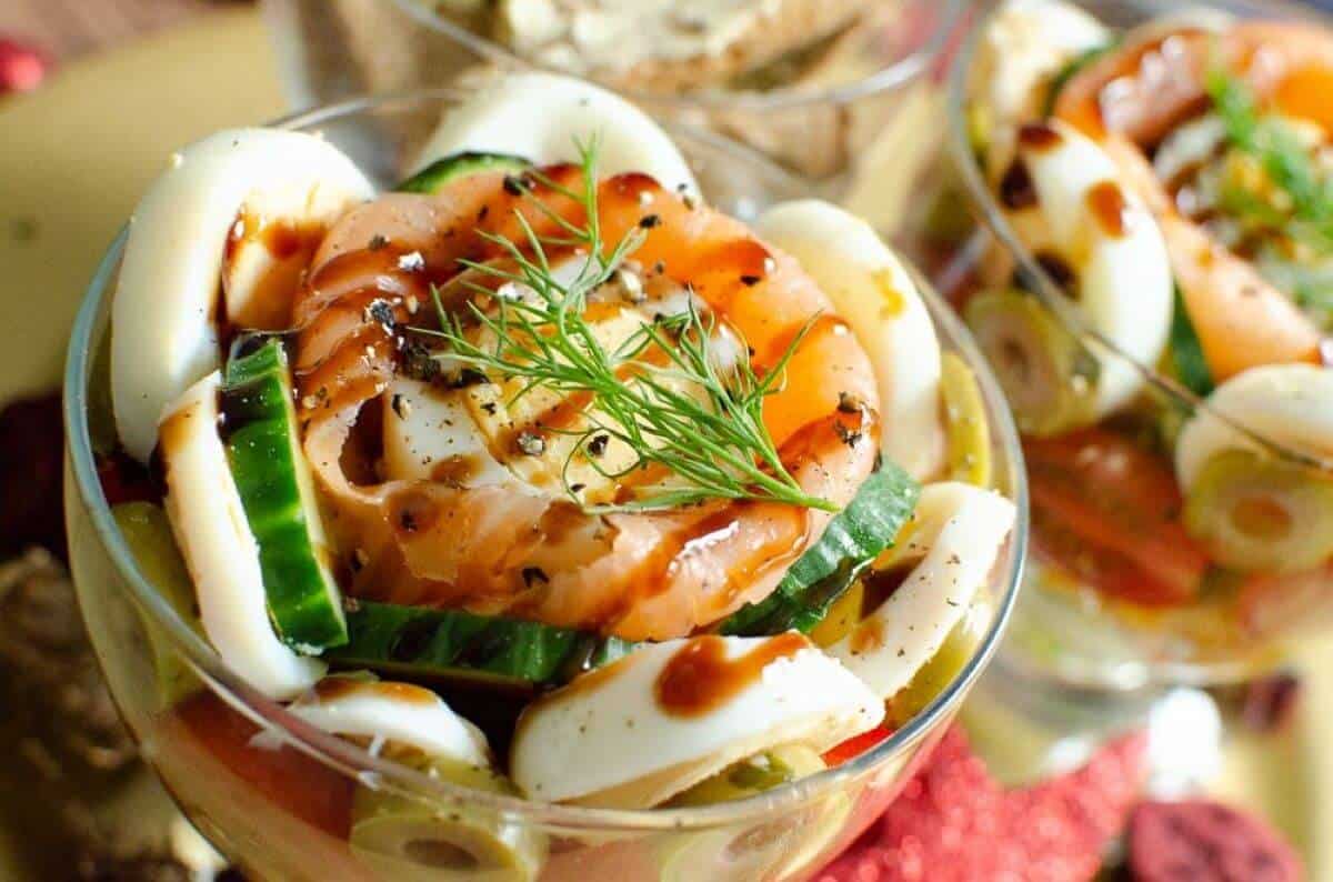 Glass with smoked salmon, eggs and cucumbers garnished with herbs. 