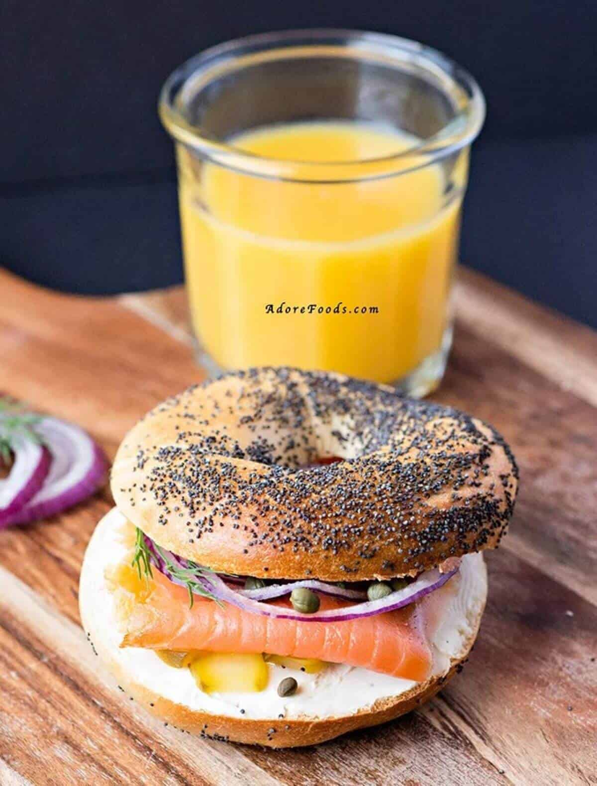 Bagel sandwich with cream cheese, smoked salmon and veggies and some orange juice on the side. 