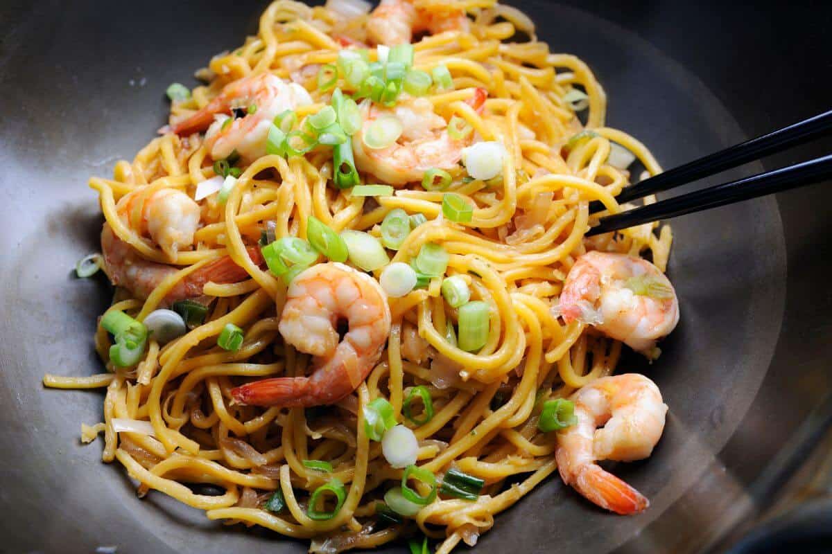 A bowl of egg noodles with prawns and spring onion