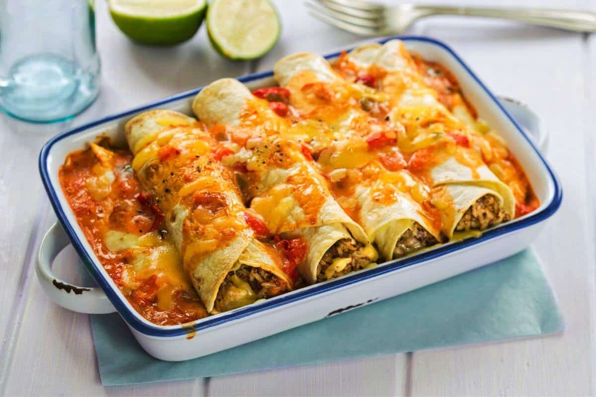 Baked enchiladas with melted cheese on top and tomato sauce in the dish