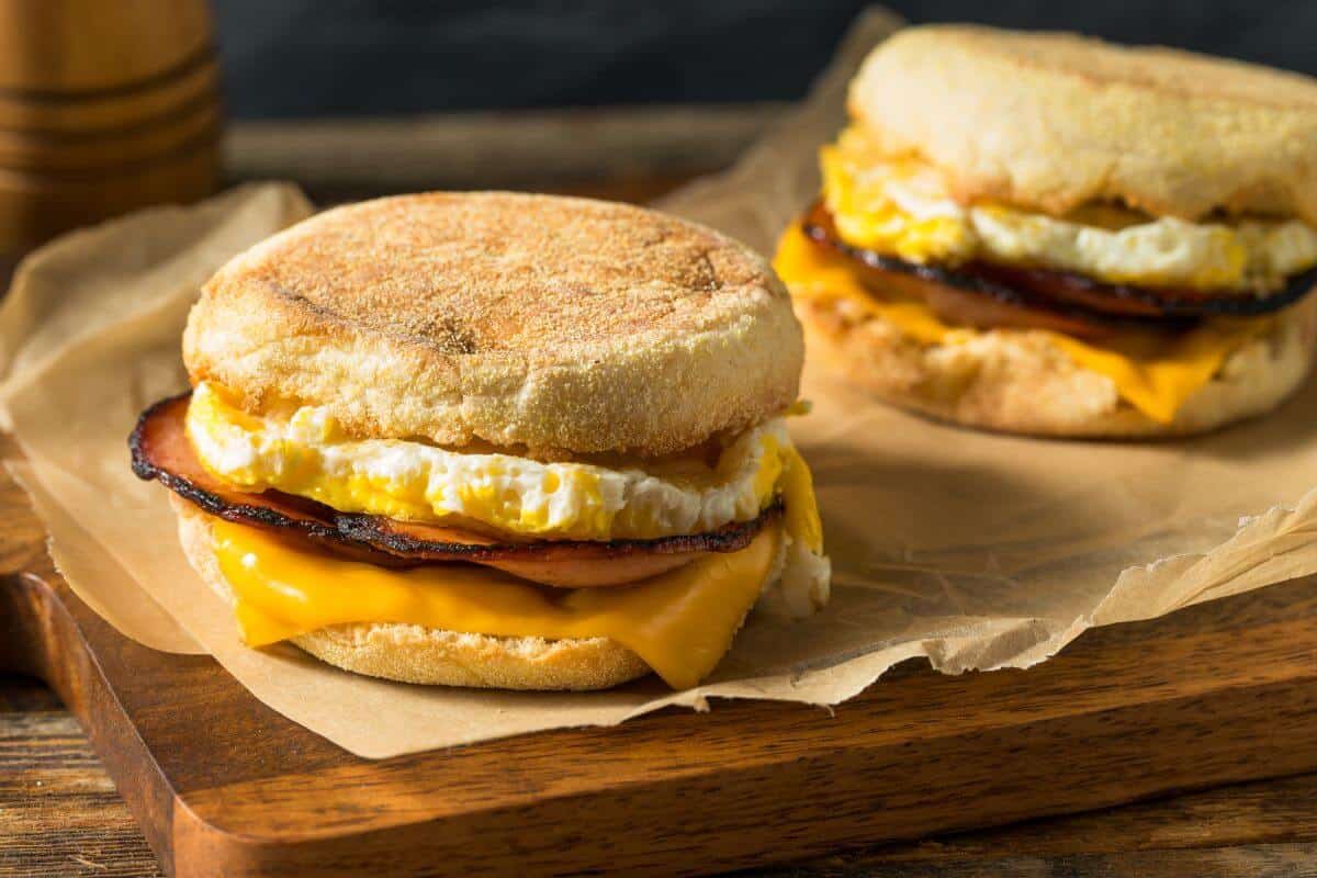 2 English muffins, sliced in half and filled with a fried egg, slice and cheese and bacon