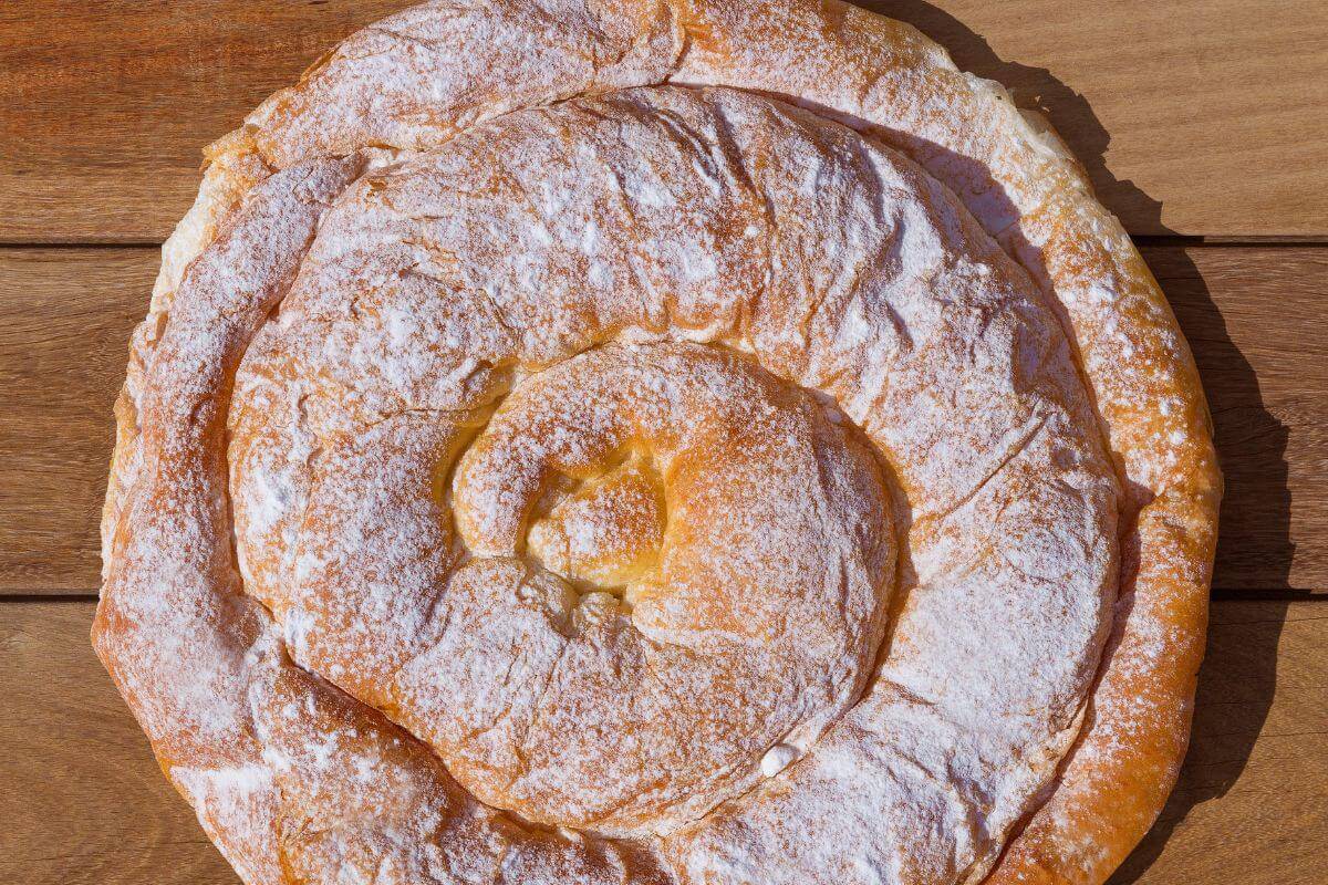 An ensaimada, dusted with sugar on a wooden table