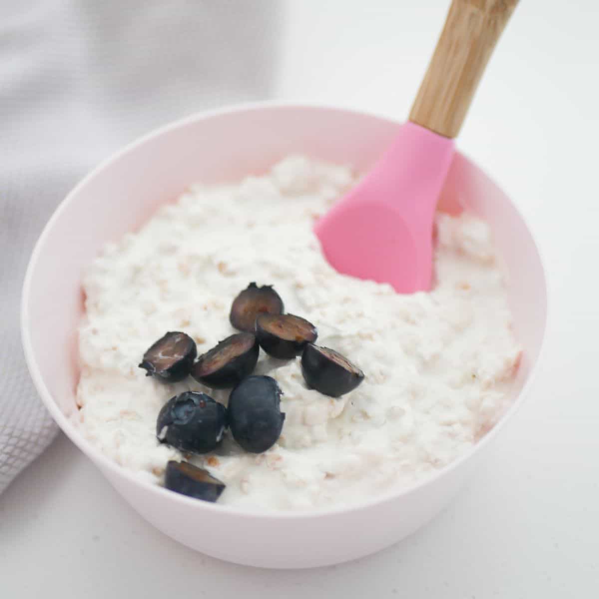 yogurt blueberry overnight oats for baby in pink bowl with pink silicone spoon