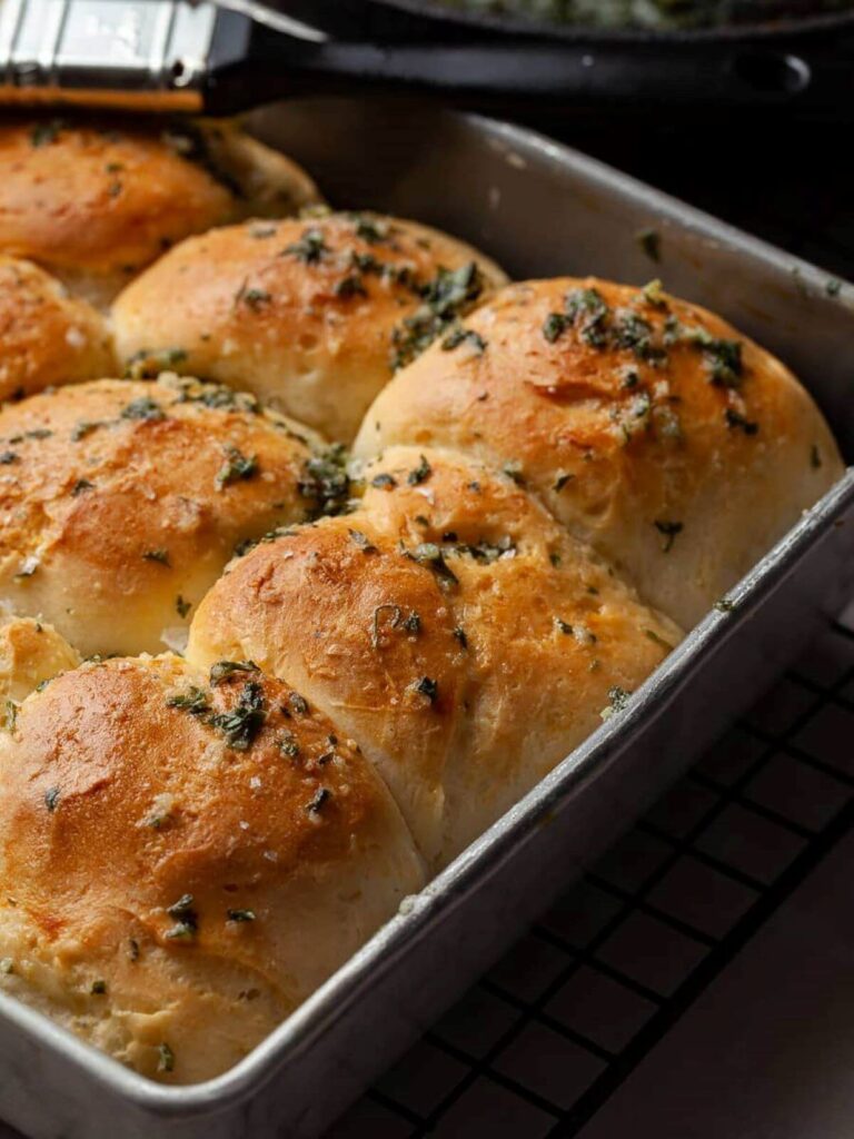 Baking tin with bread rolls sprinkled with garlic. 